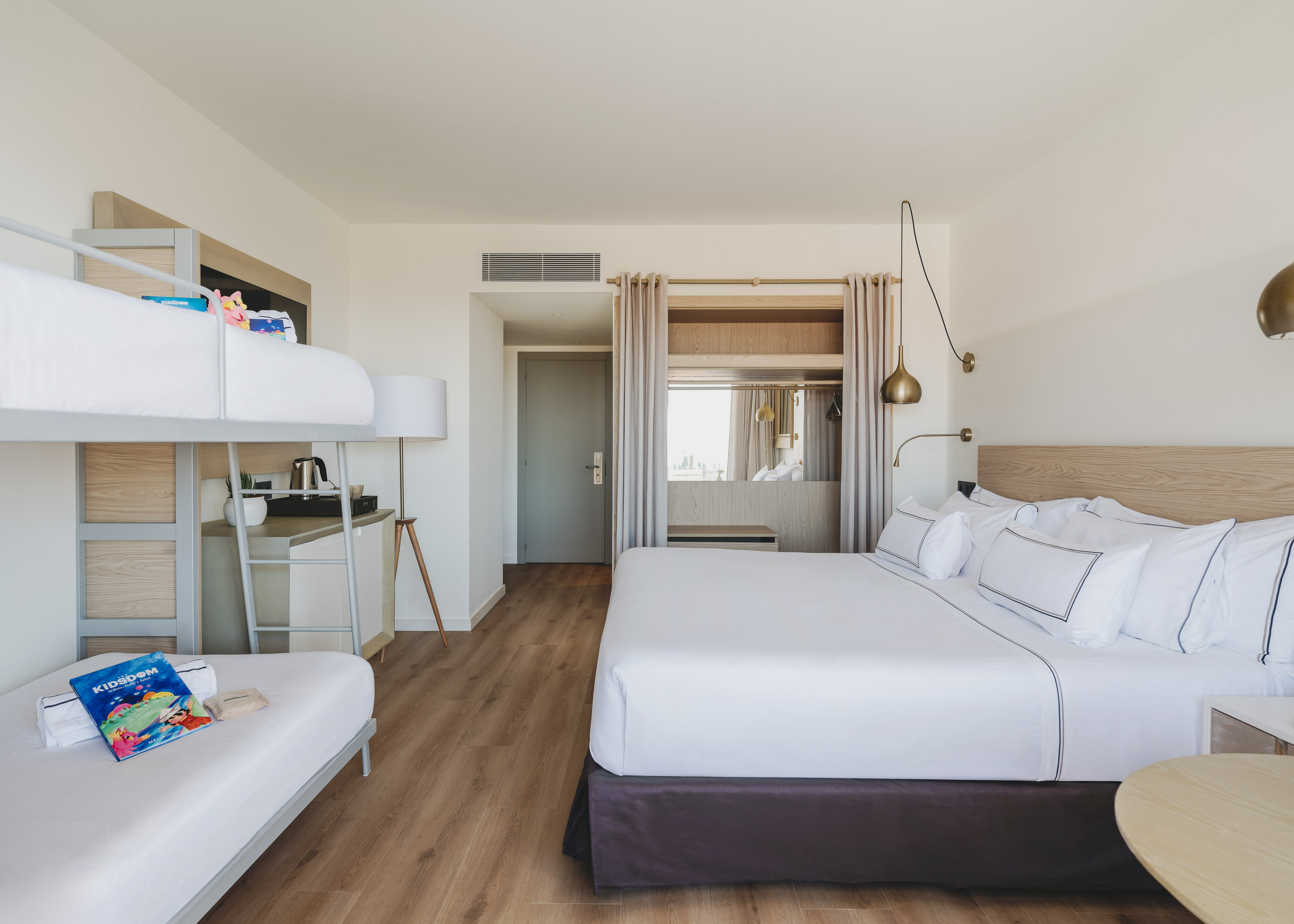 Habitación familiar de hotel con cama king, literas y diseño moderno.