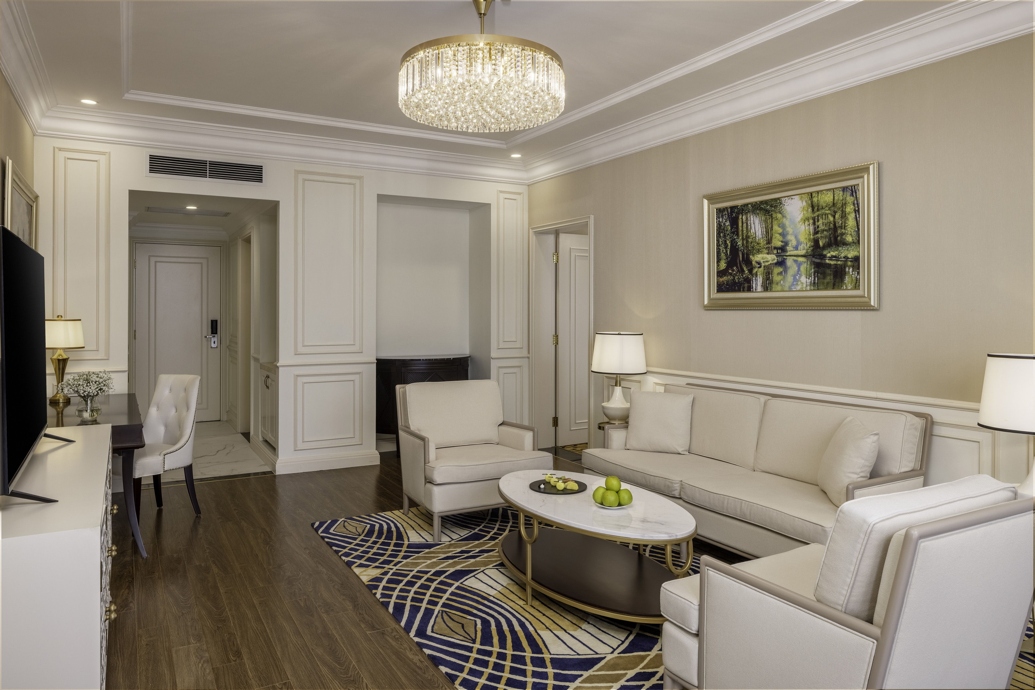 Elegant suite living room with neutral decor, crystal chandelier, and geometric rug.