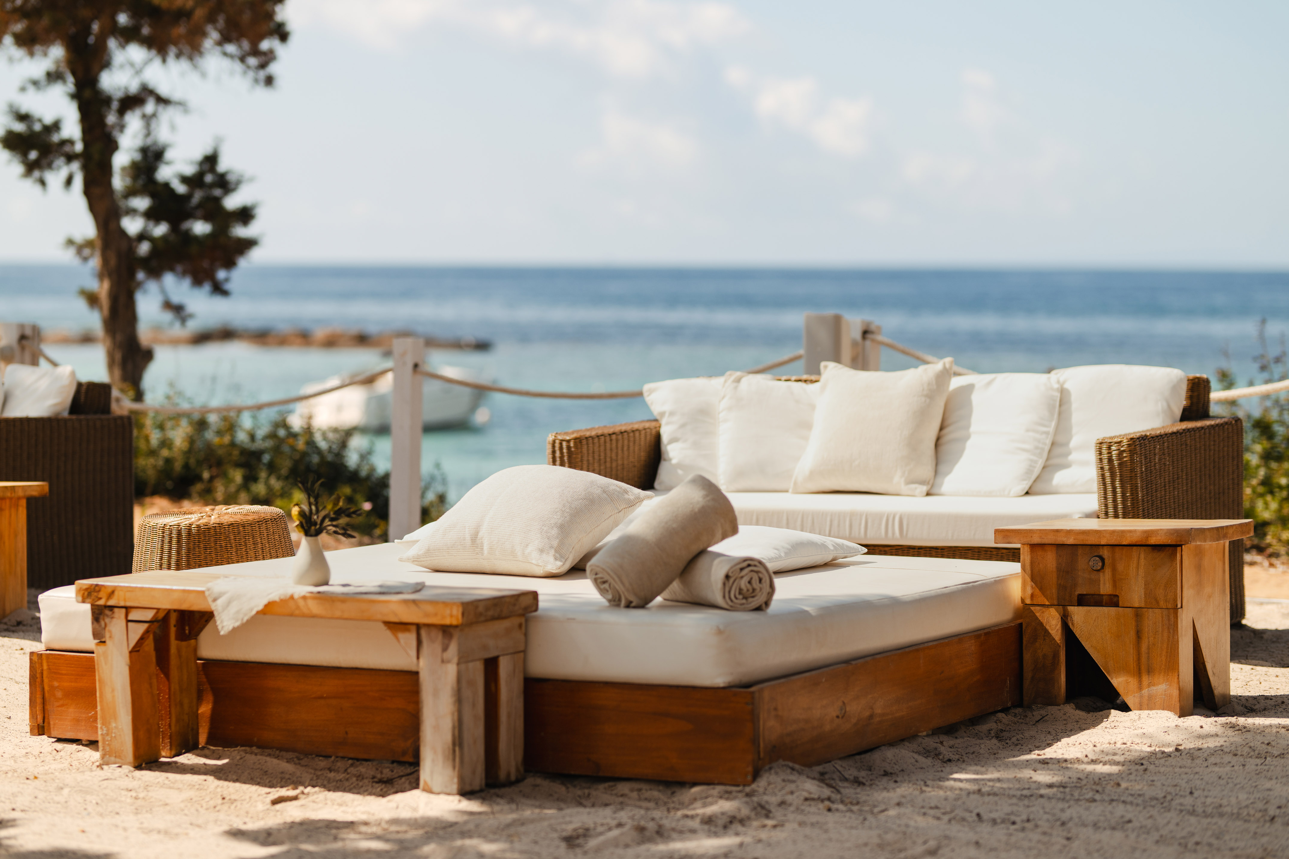 Coastal resort lounge with wooden daybeds, wicker sofa, and ocean view.
