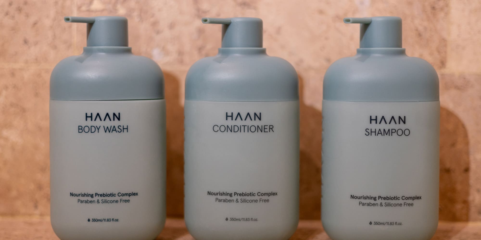 Three HAAN brand pump bottles for body wash, conditioner, and shampoo on tile. - Zel Room Vistas Jardín - Zel Cozumel, Cozumel