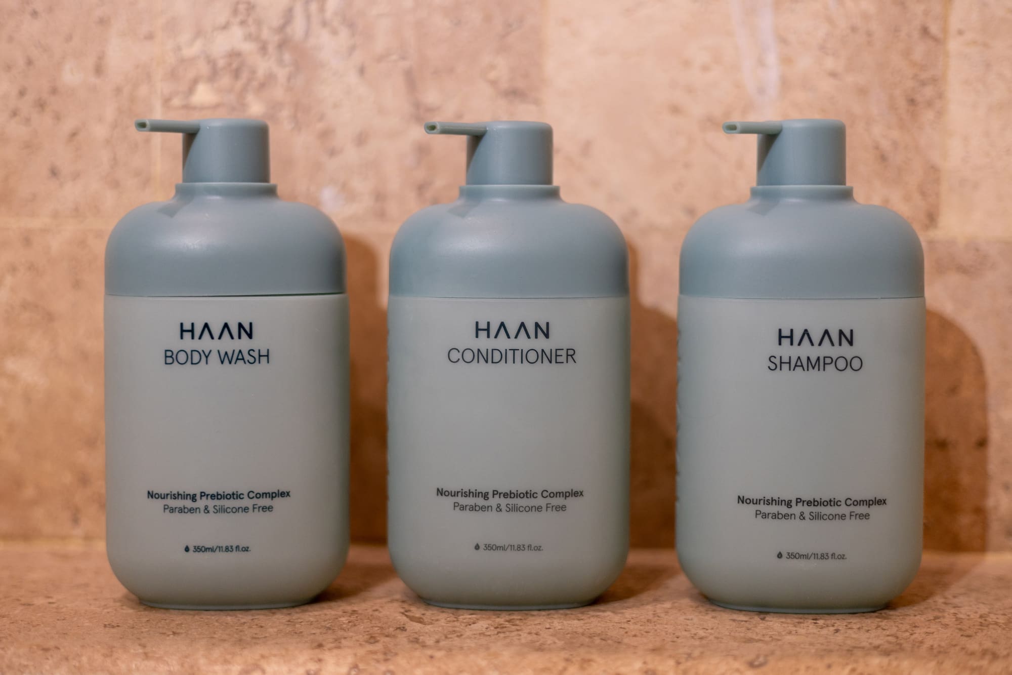 Three HAAN brand pump bottles for body wash, conditioner, and shampoo on tile. - Zel Room Vistas Jardín - Zel Cozumel, Cozumel