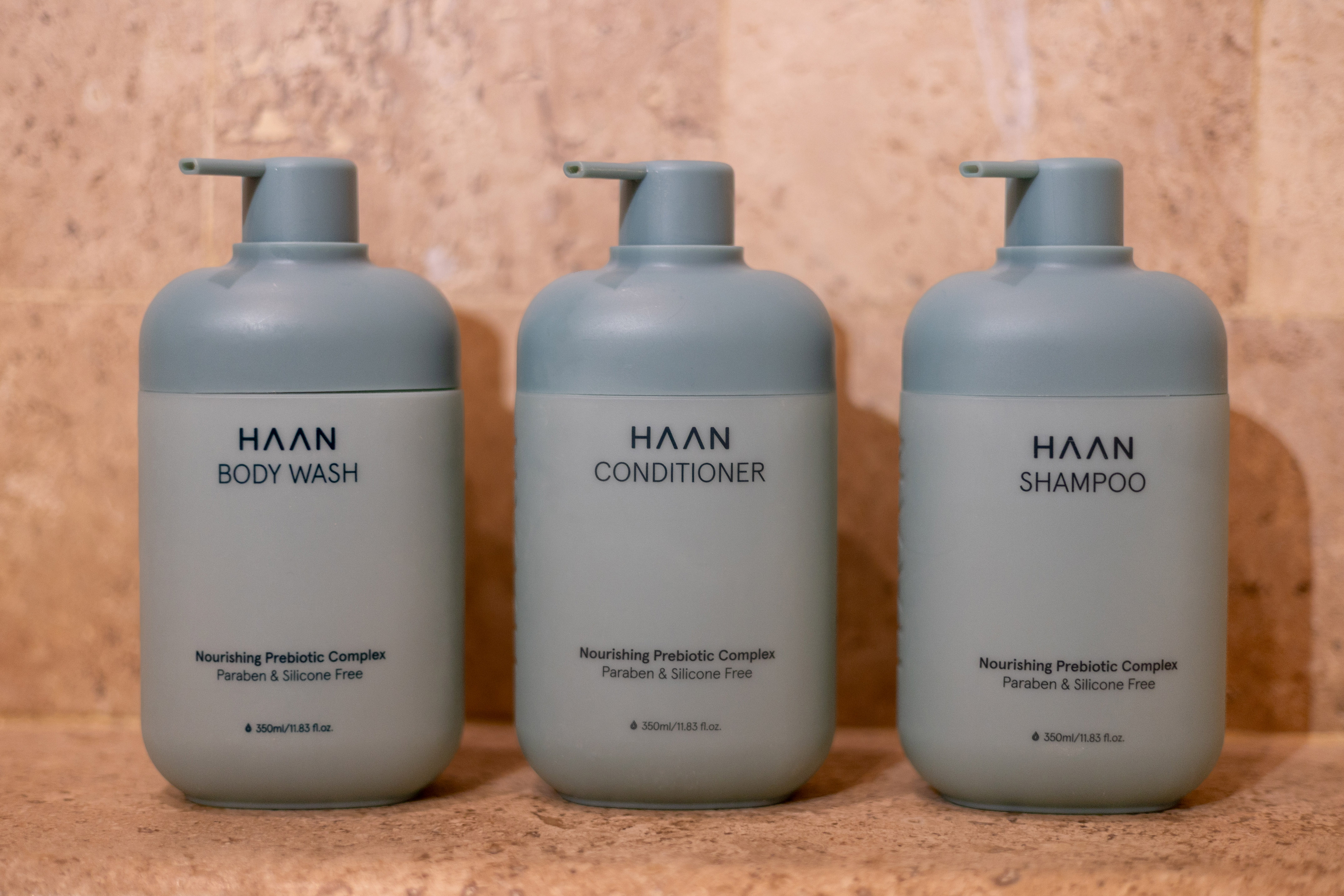 Three HAAN brand pump bottles for body wash, conditioner, and shampoo on tile. - Zel Room Vistas Jardín - Zel Cozumel, Cozumel