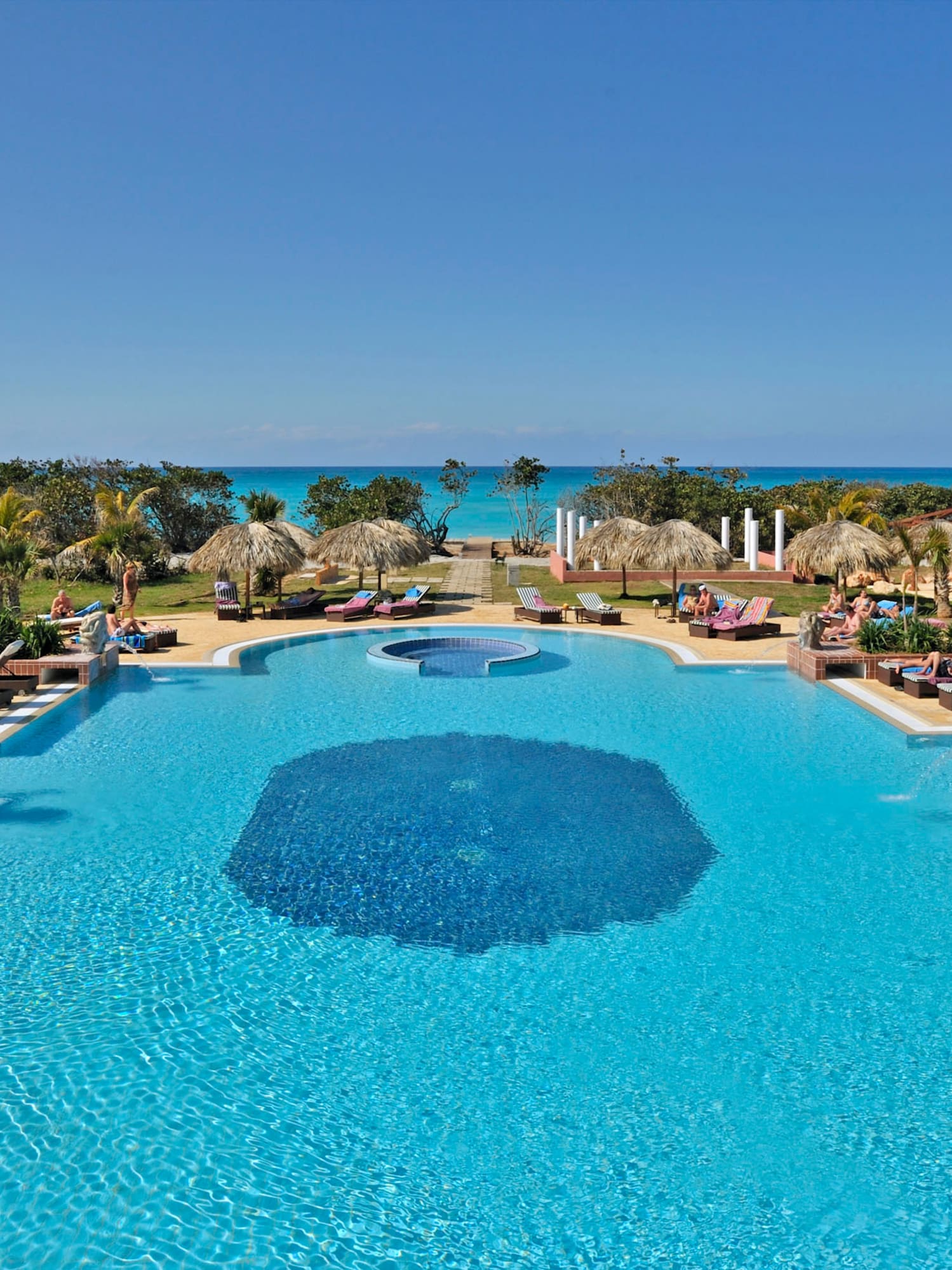 a pool with umbrellas and chairs and a beach