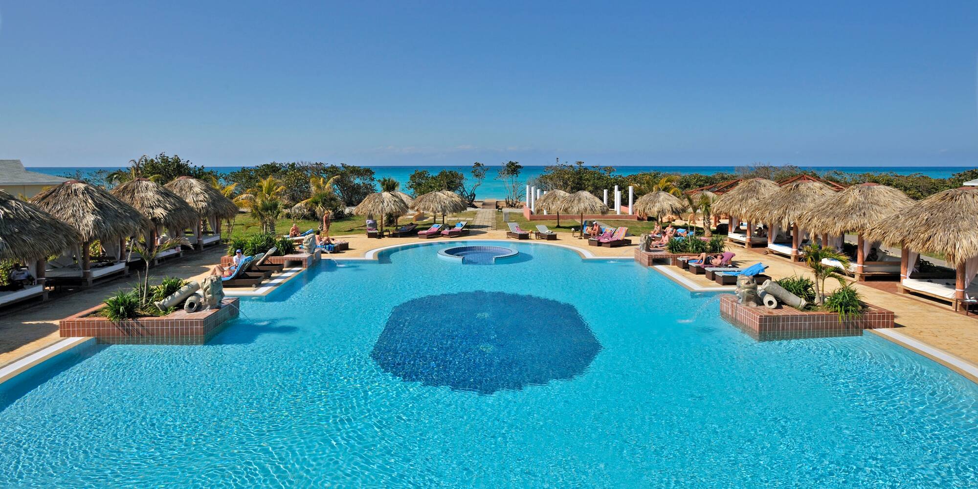 a pool with umbrellas and chairs and a beach