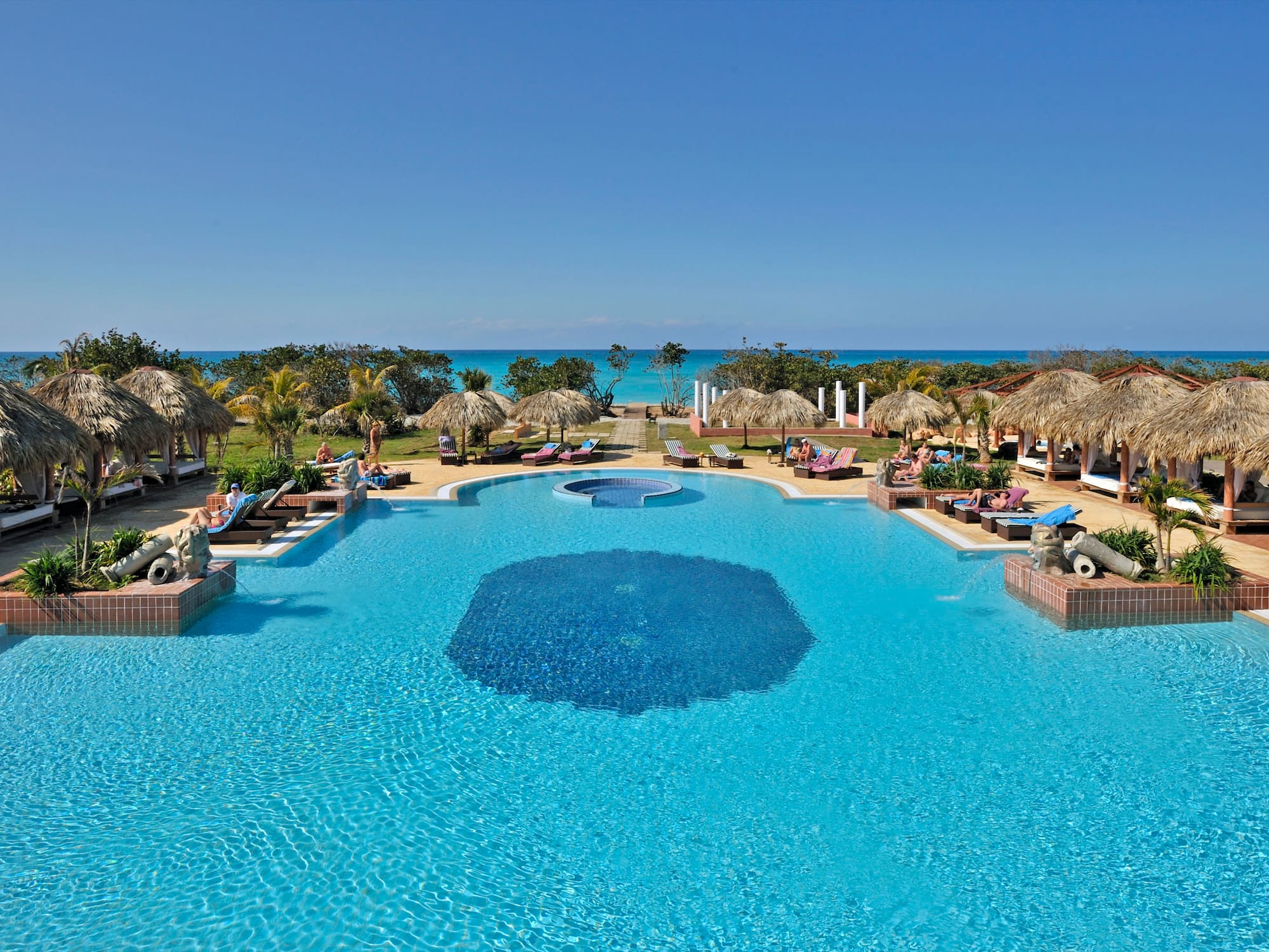 a pool with umbrellas and chairs and a beach