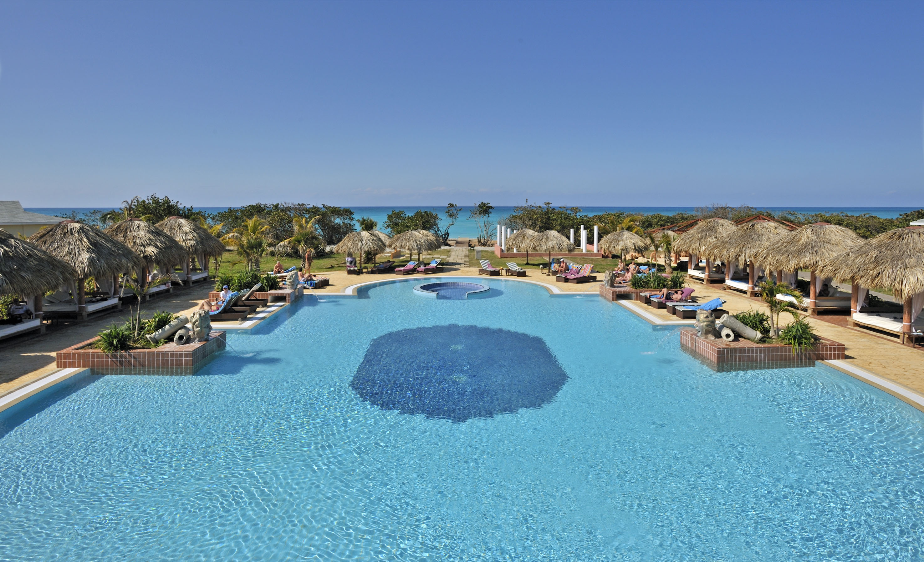 a pool with umbrellas and chairs and a beach