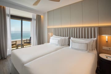 a room with two beds and a window overlooking the ocean