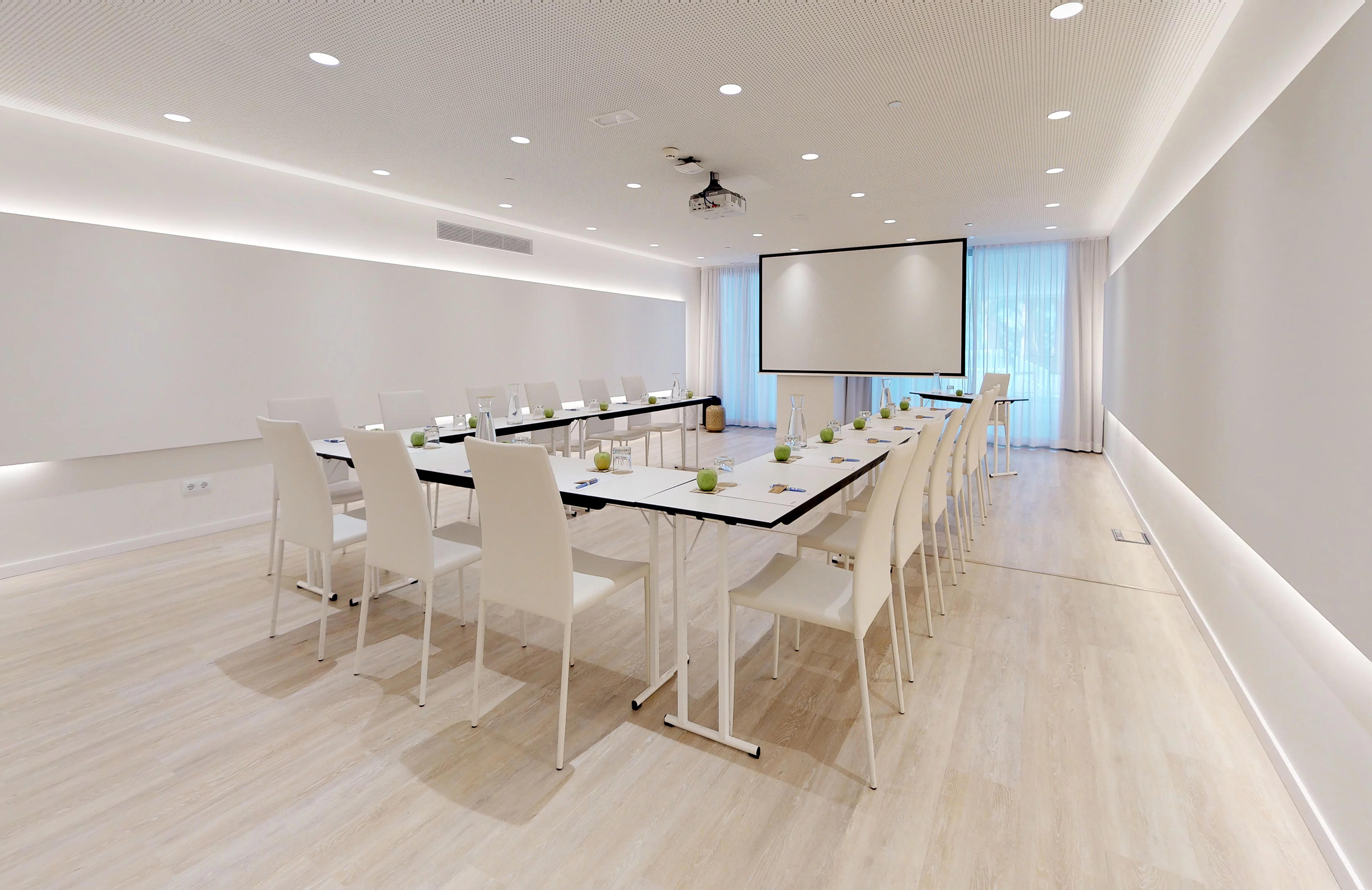 Modern meeting room with U-shaped table, projector screen, and white chairs.
