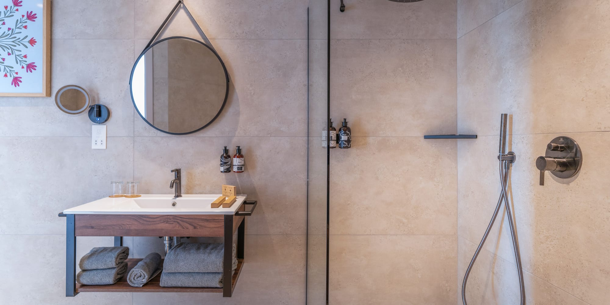 Modern bathroom with floating vanity, round mirror, and walk-in shower.