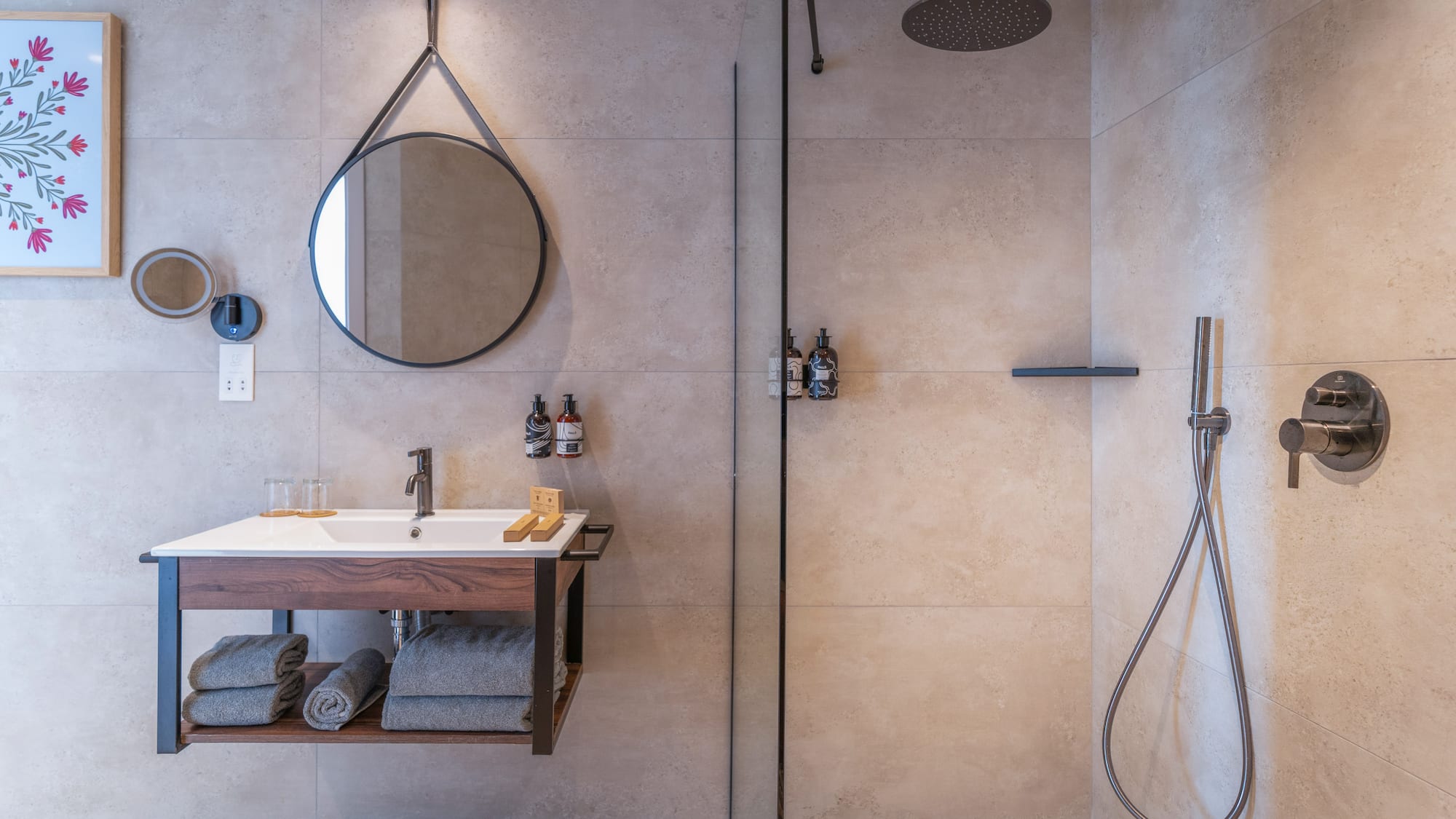 Modern bathroom with floating vanity, round mirror, and walk-in shower.