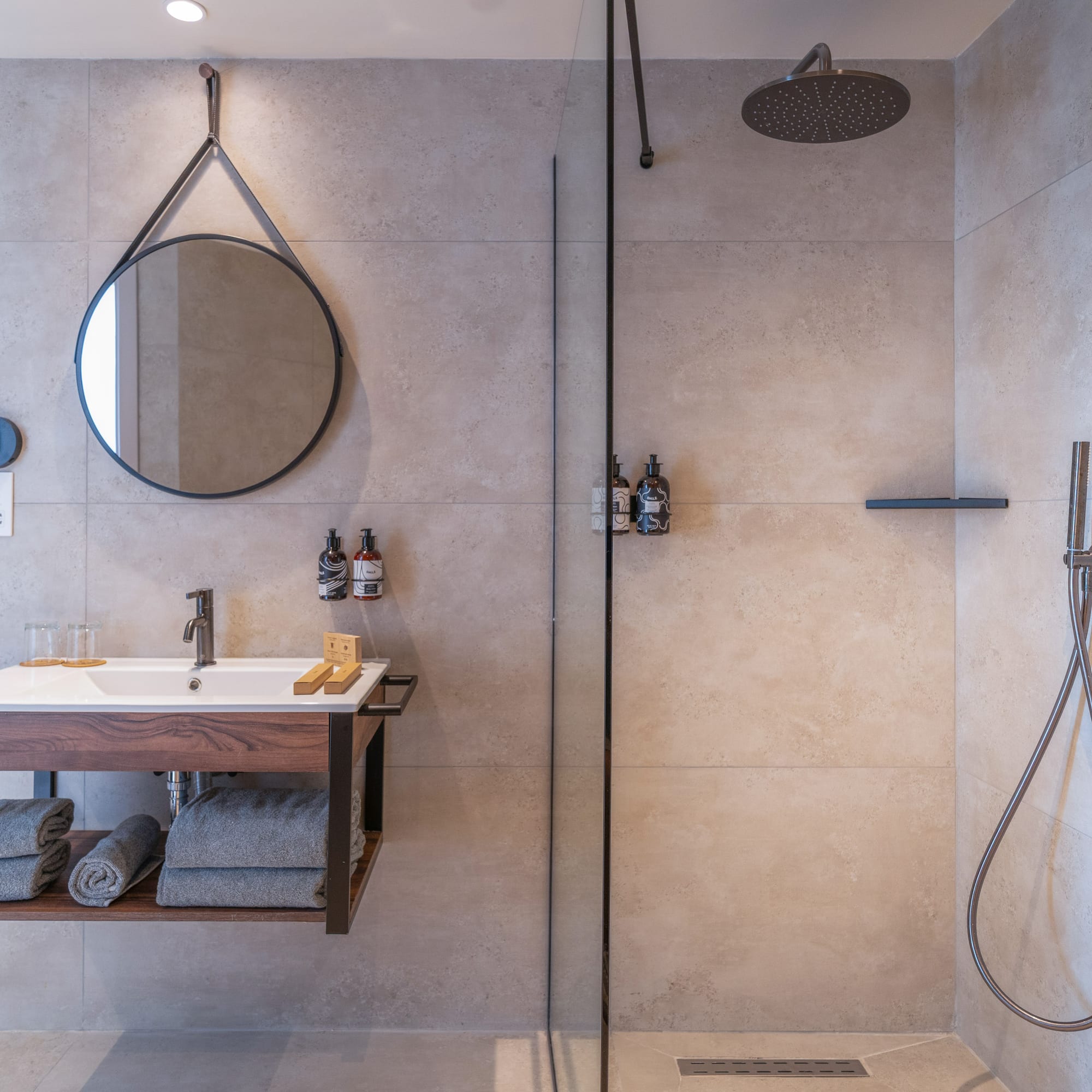 Modern bathroom with floating vanity, round mirror, and walk-in shower.