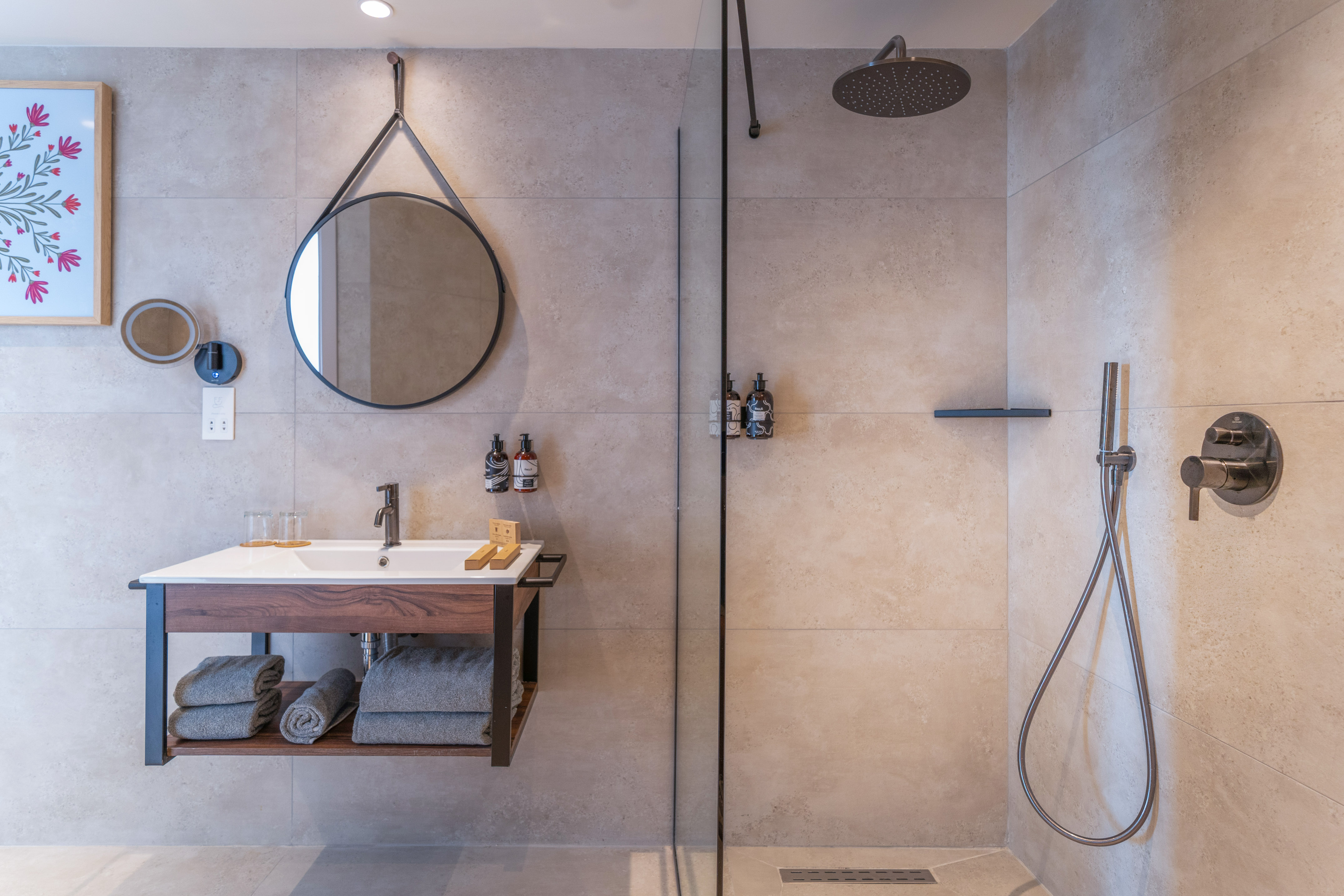 Modern bathroom with floating vanity, round mirror, and walk-in shower.