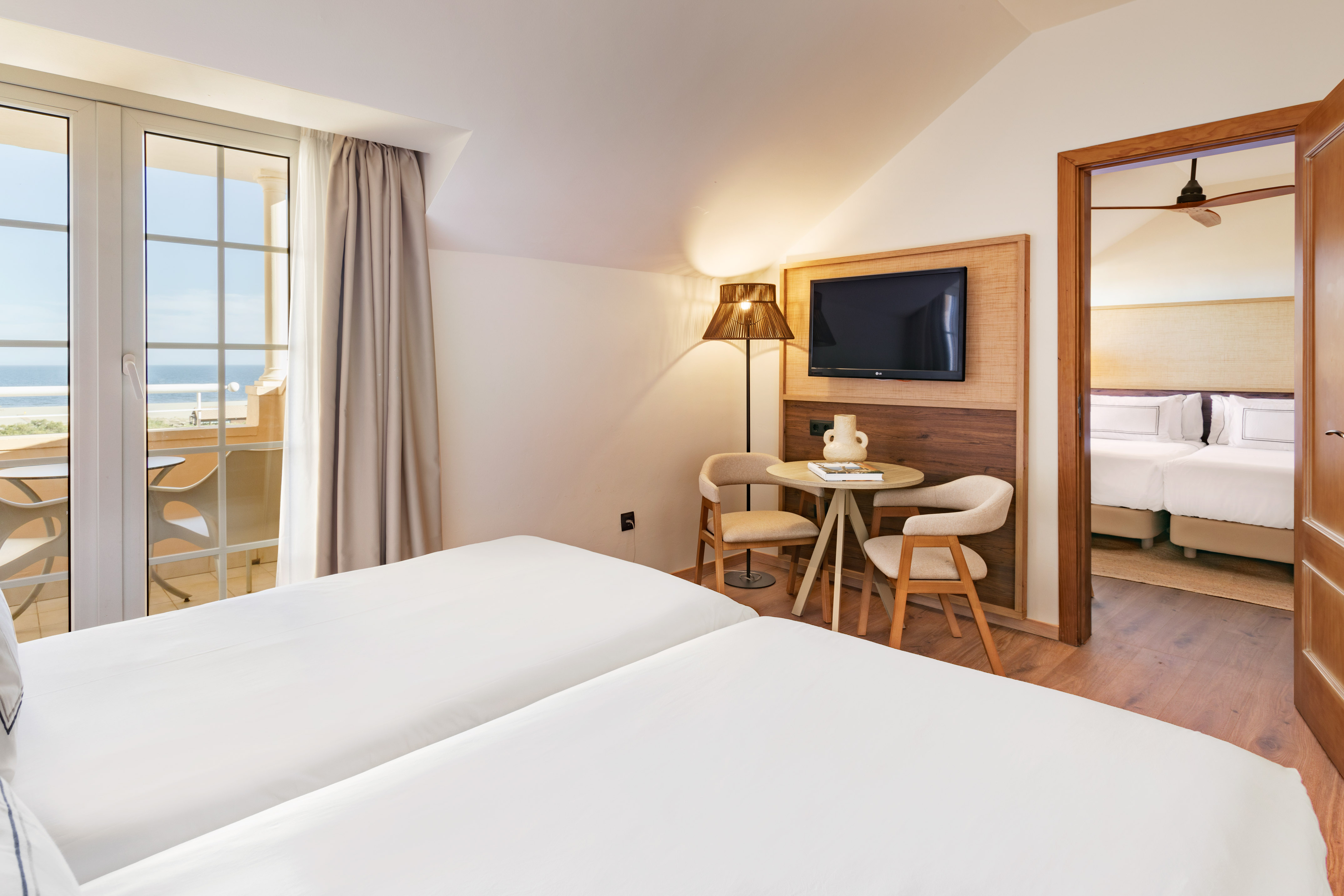 Twin beds hotel room, ocean view balcony, TV, and connecting bedroom.