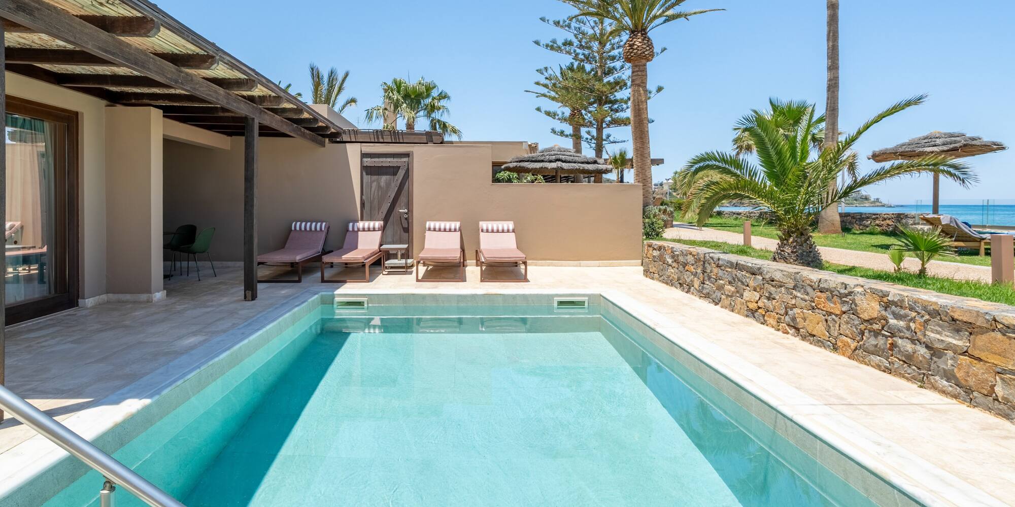 Luxury hotel room with private pool, sun loungers, and tropical ocean view.