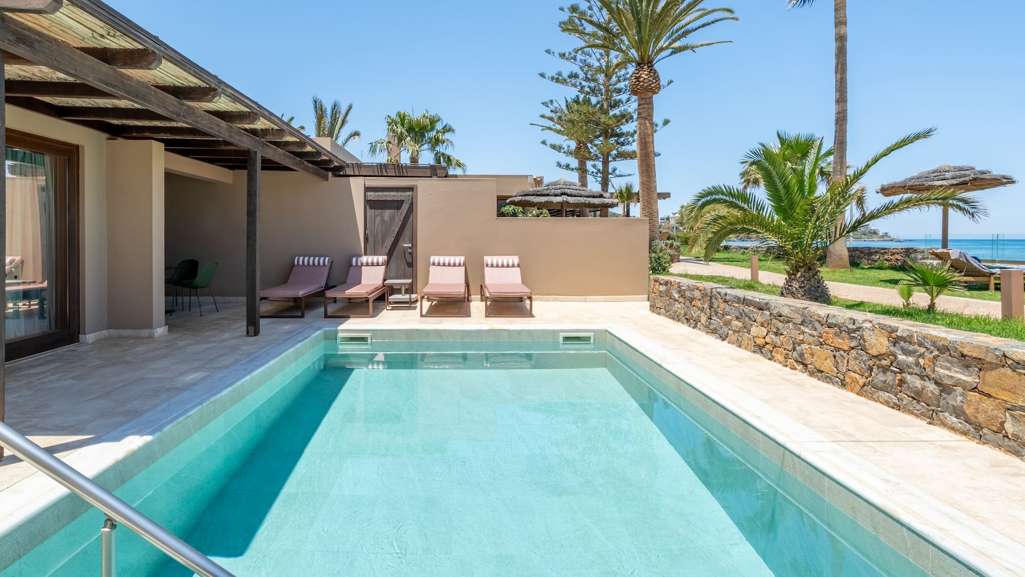 Luxury hotel room with private pool, sun loungers, and tropical ocean view.
