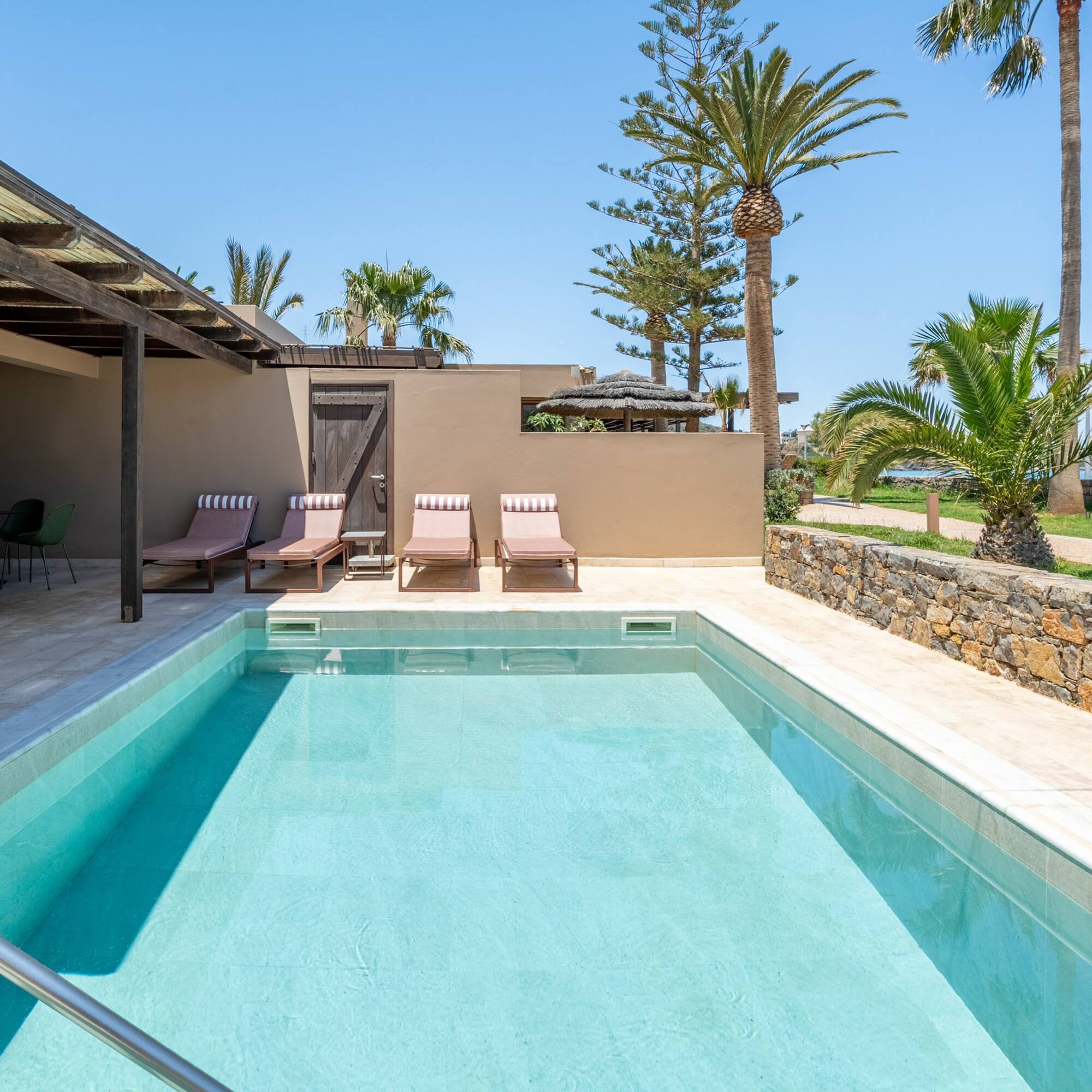 Luxury hotel room with private pool, sun loungers, and tropical ocean view.