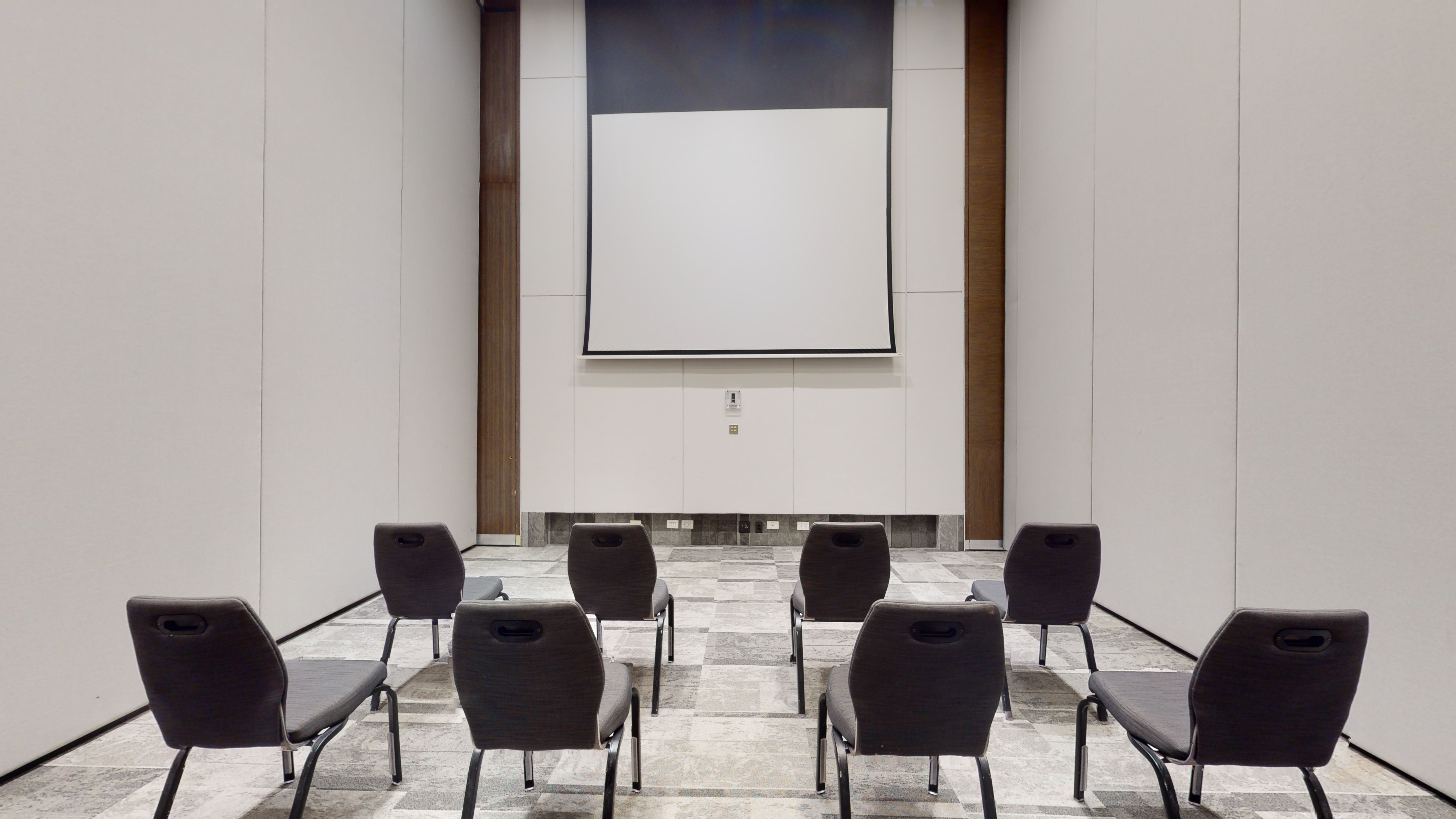 Modern conference room with presentation screen and empty chairs.