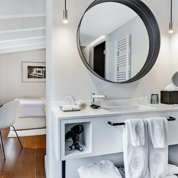 uma cama com almofadas brancas e um espelho em um quarto
