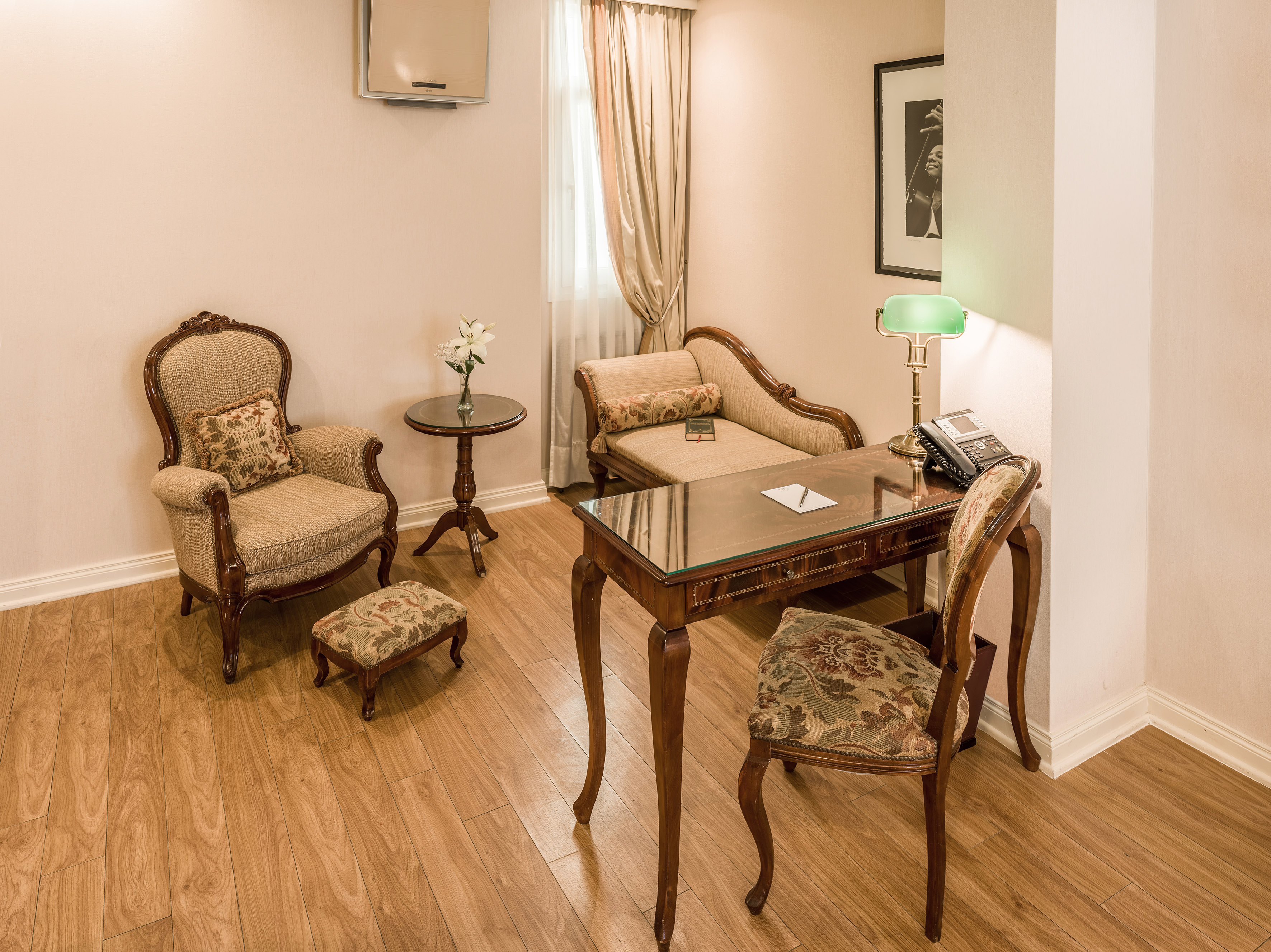 Elegant hotel room interior with classic furniture, desk, and chaise lounge.