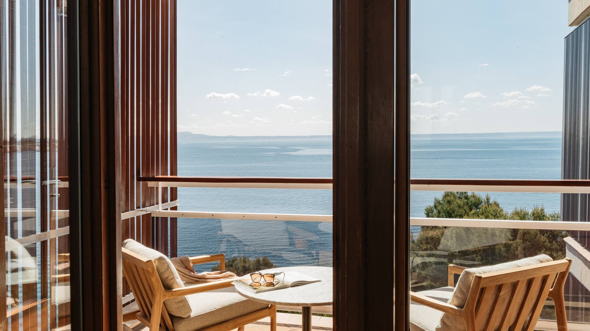 a balcony with chairs and a table overlooking the ocean