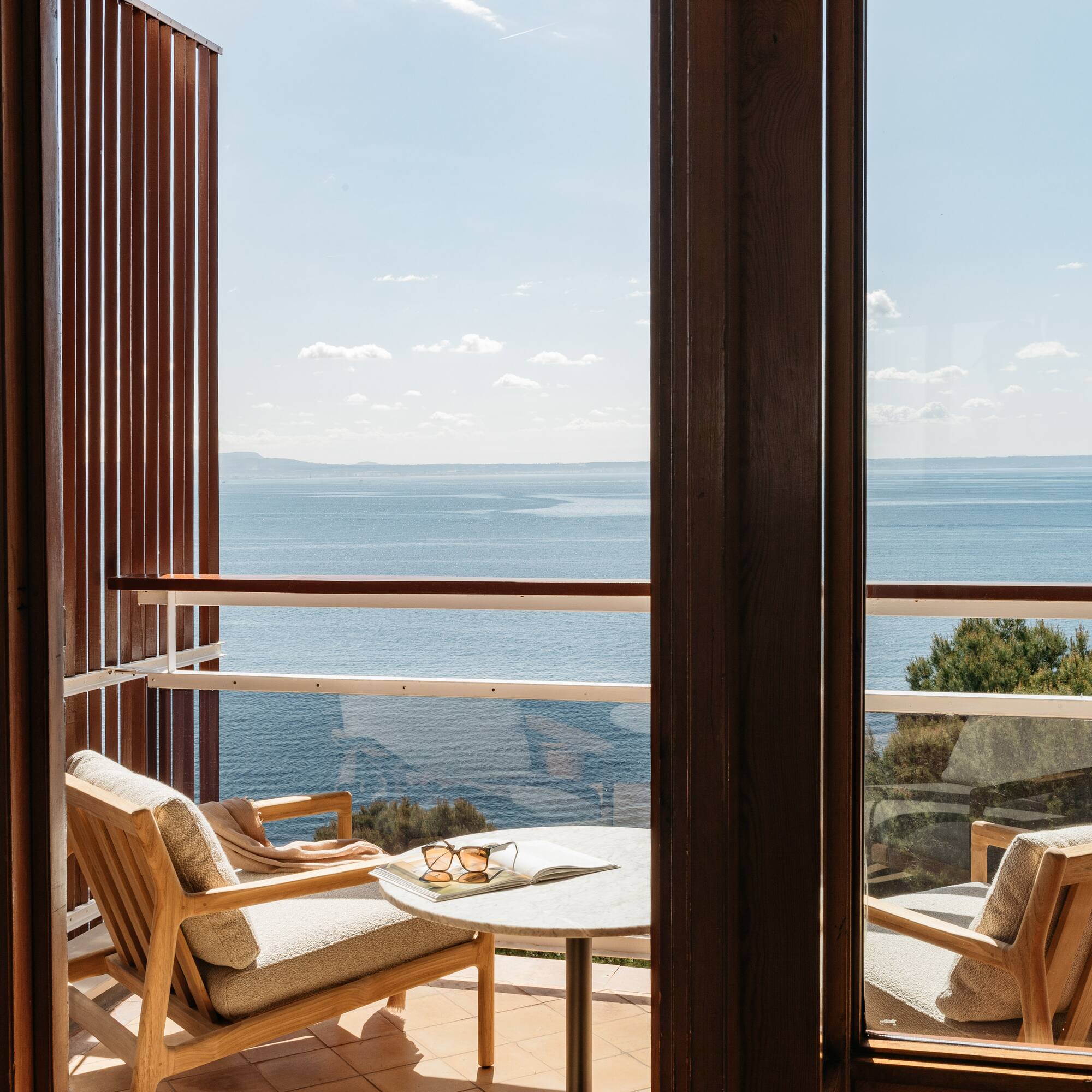 a balcony with chairs and a table overlooking the ocean