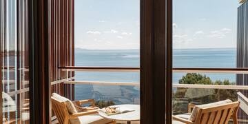 a balcony with chairs and a table overlooking the ocean