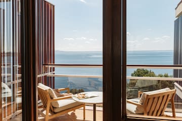 a balcony with chairs and a table overlooking the ocean