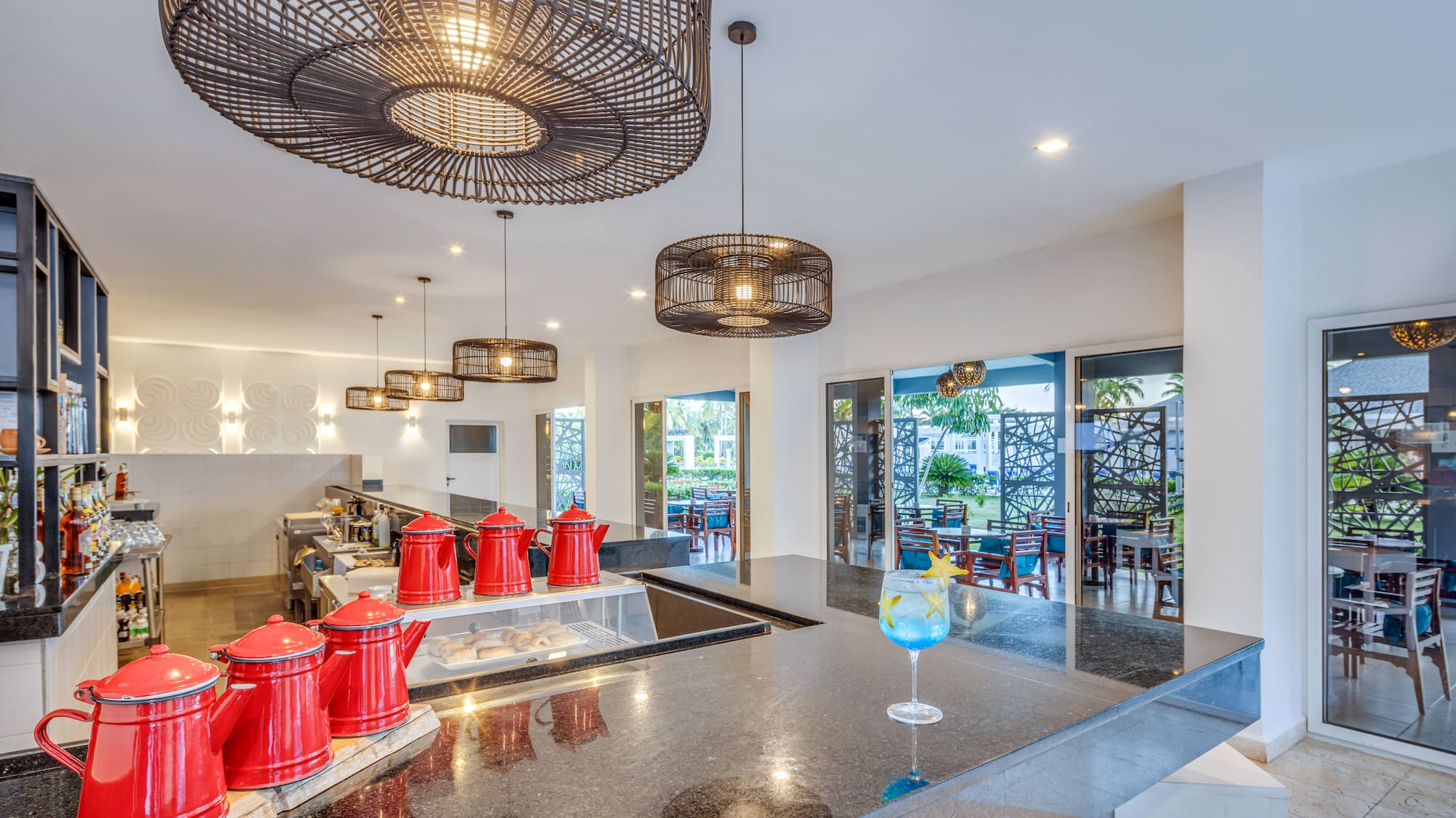 a counter with red teapots and a drink glass in front of a glass