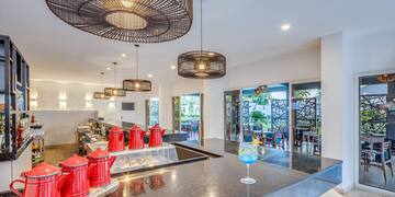 a counter with red teapots and a drink glass in front of a glass