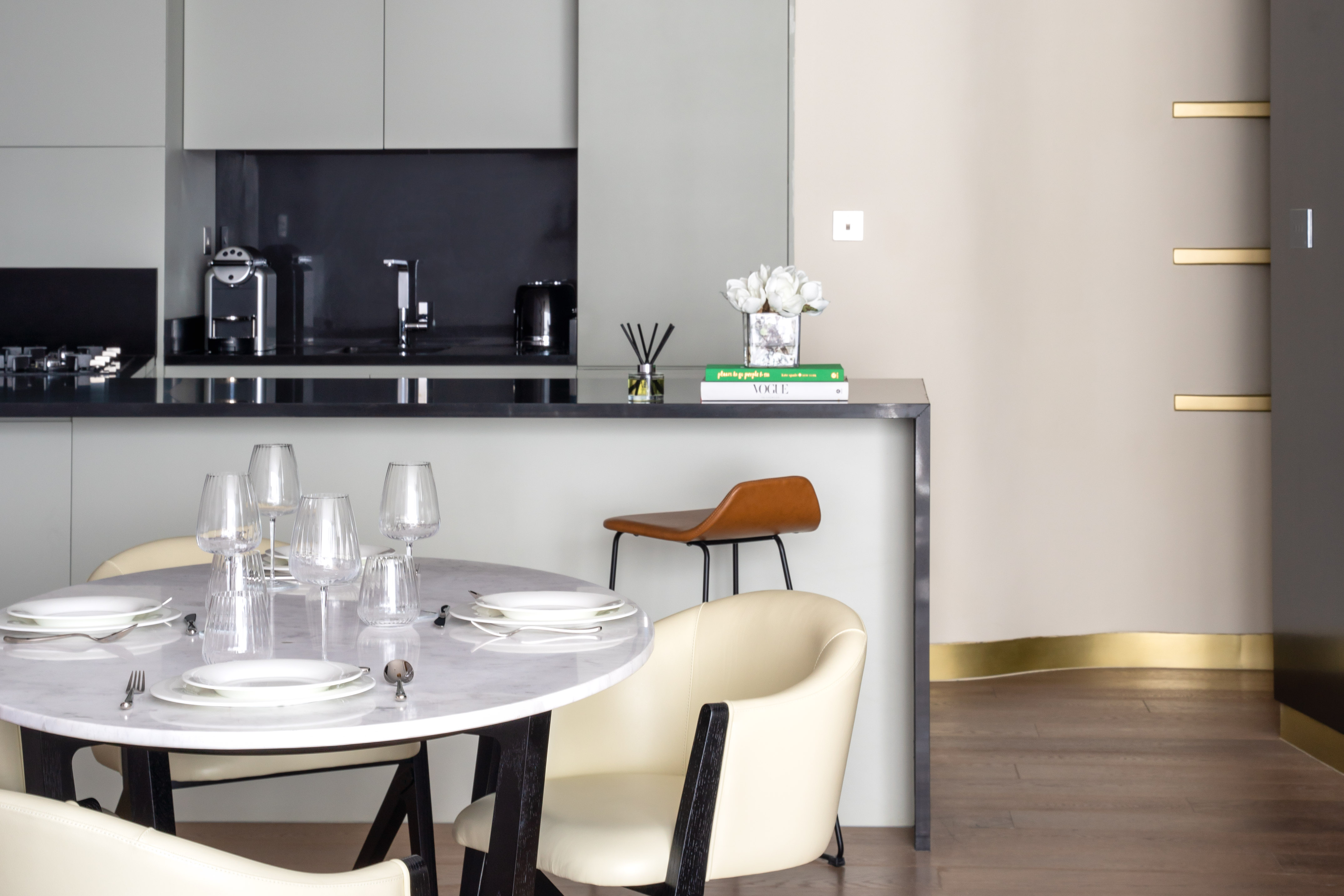 Modern kitchen-diner with marble table, white chairs, and stylish decor.