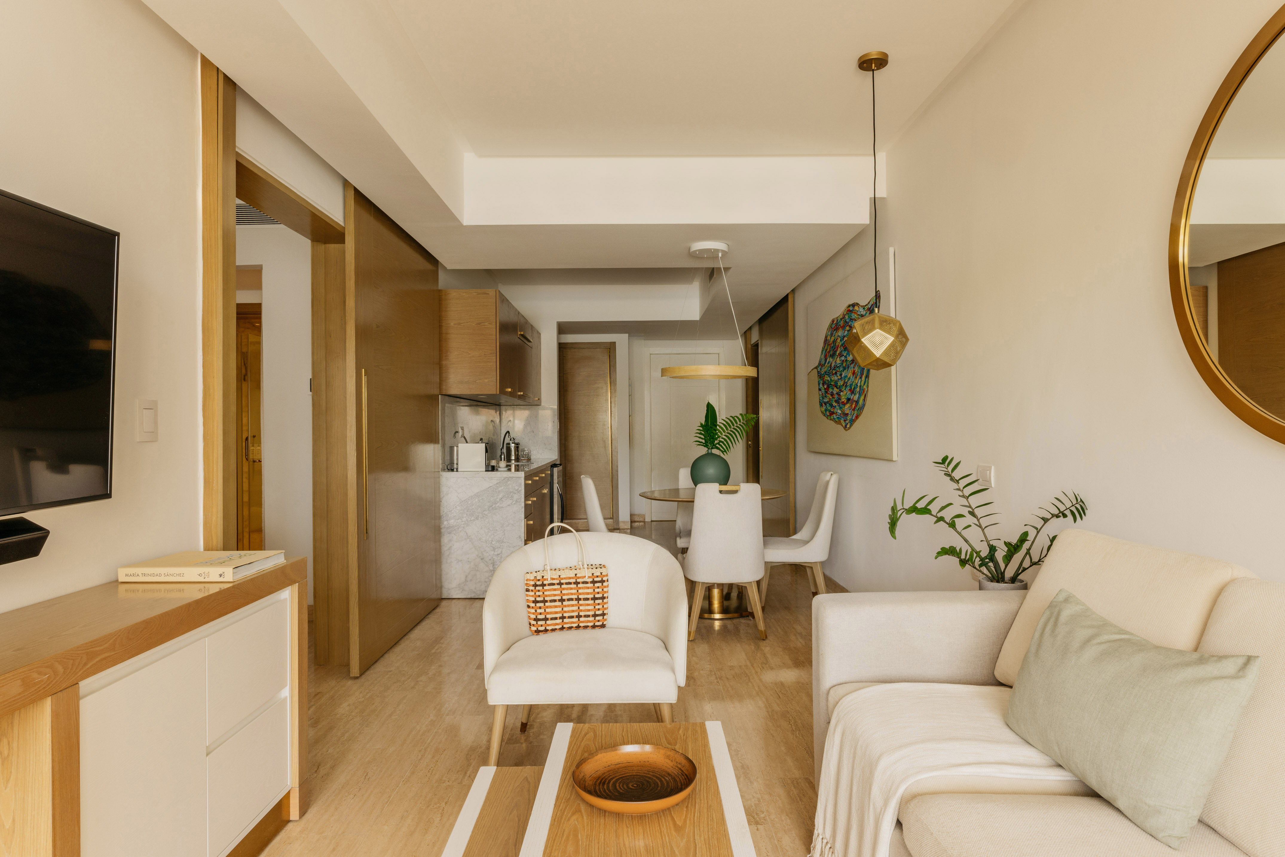 Modern open-concept living & dining room with neutral furniture, kitchen area.