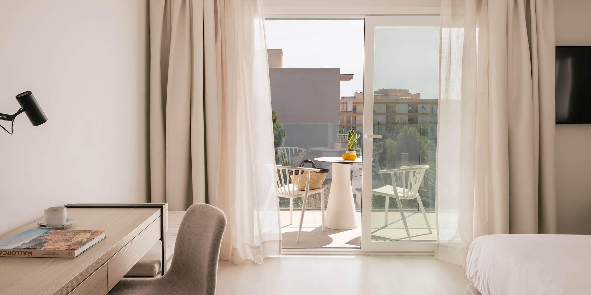 Modern hotel room in Mallorca with a desk, bed, and balcony.