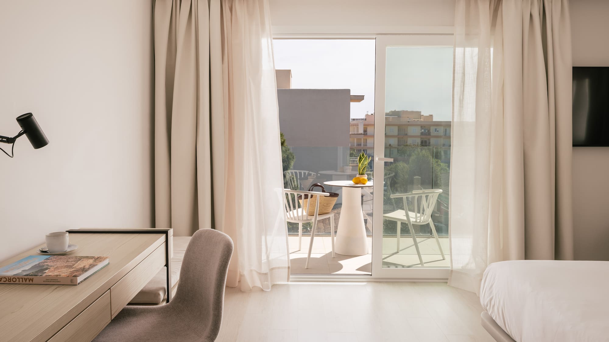 Modern hotel room in Mallorca with a desk, bed, and balcony.