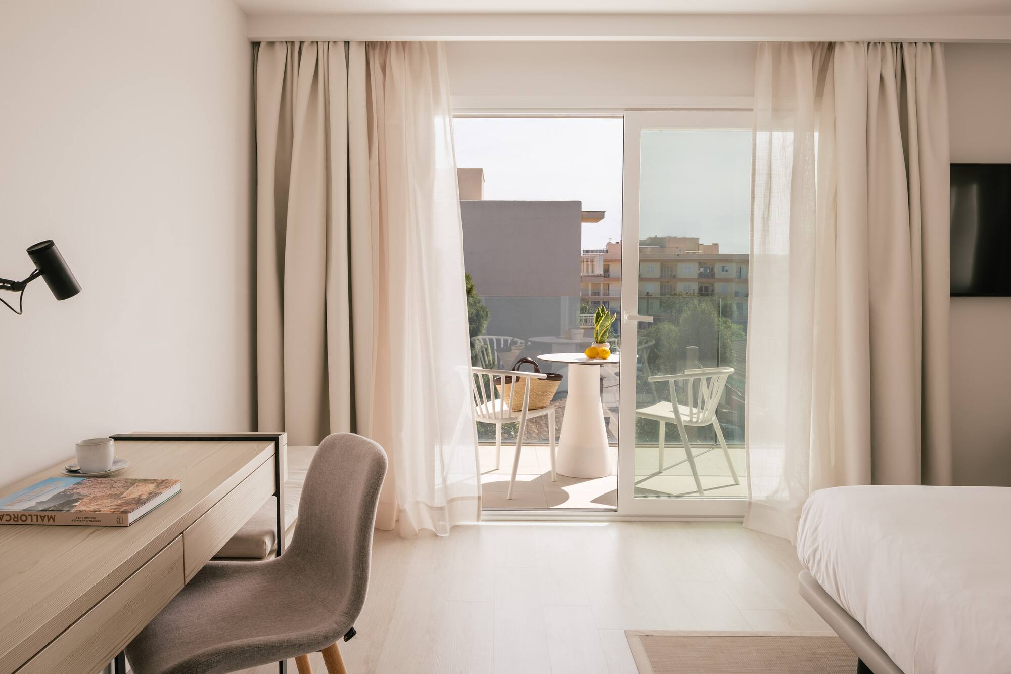 Habitación de hotel moderna con escritorio, cama y balcón amueblado.