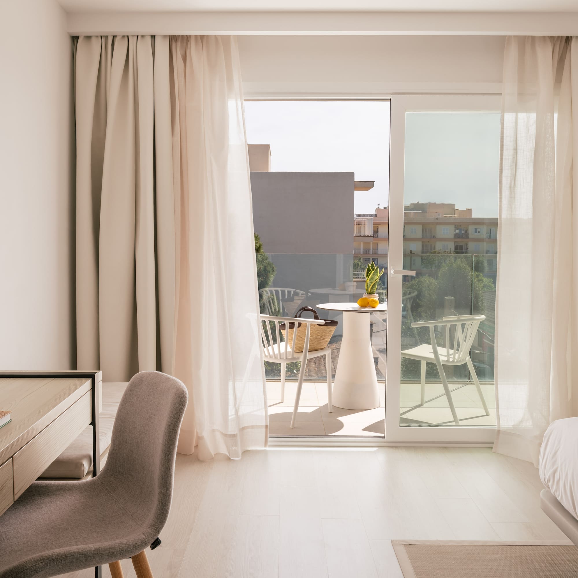 Modern hotel room in Mallorca with a desk, bed, and balcony.