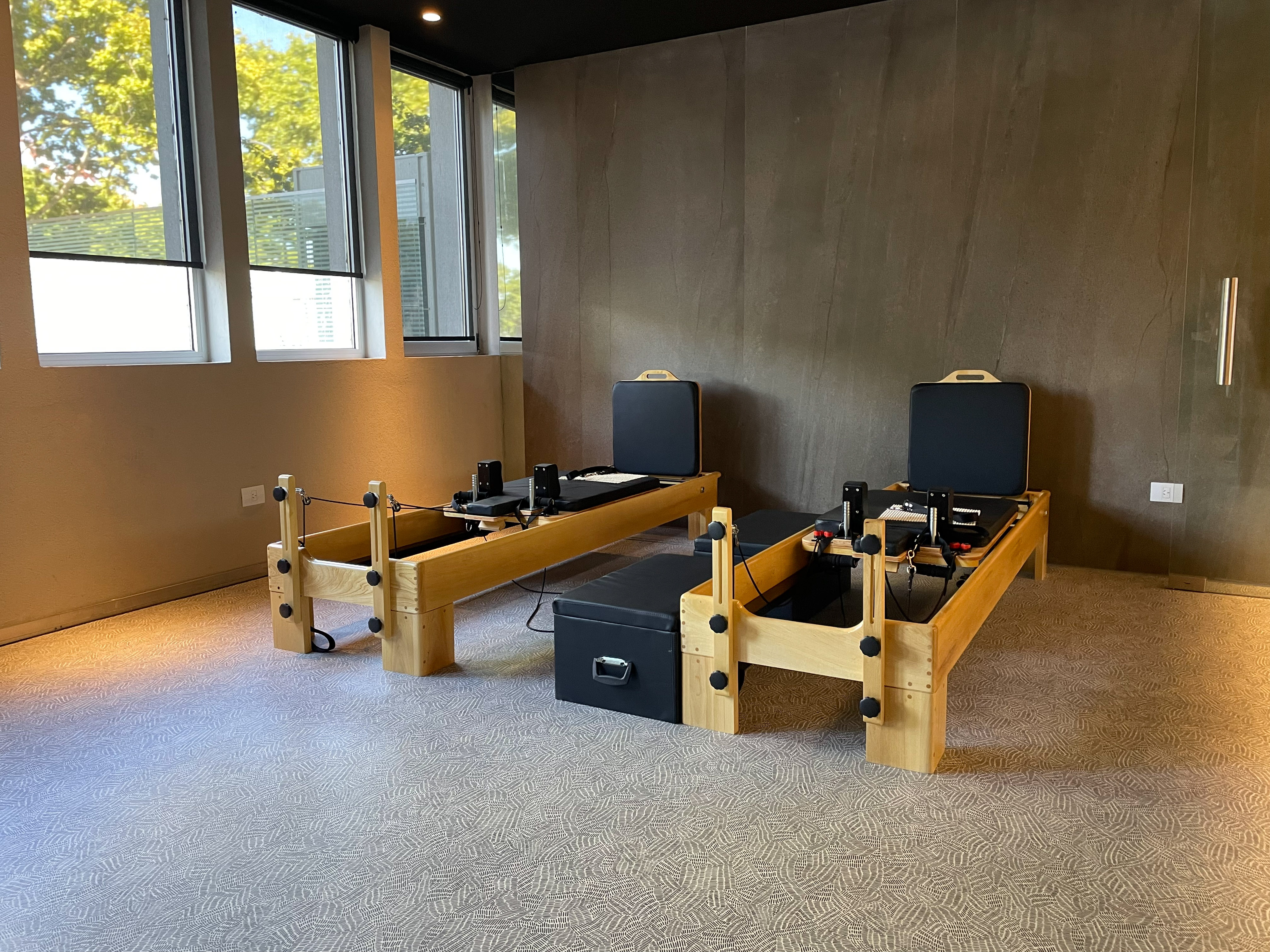 Two wooden Pilates reformers in a modern studio with natural light.