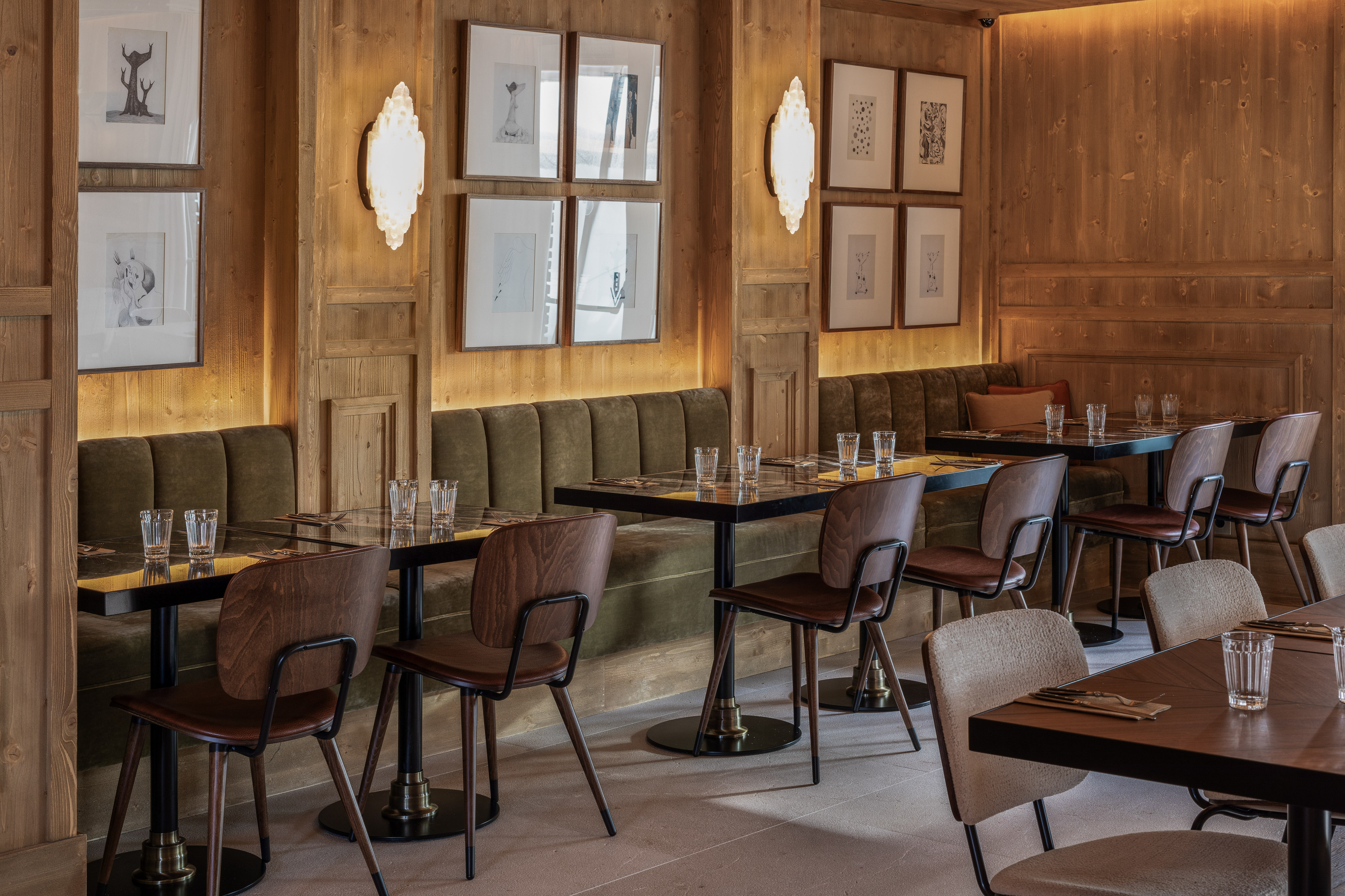 Modern wooden restaurant interior with green booths and framed artwork.