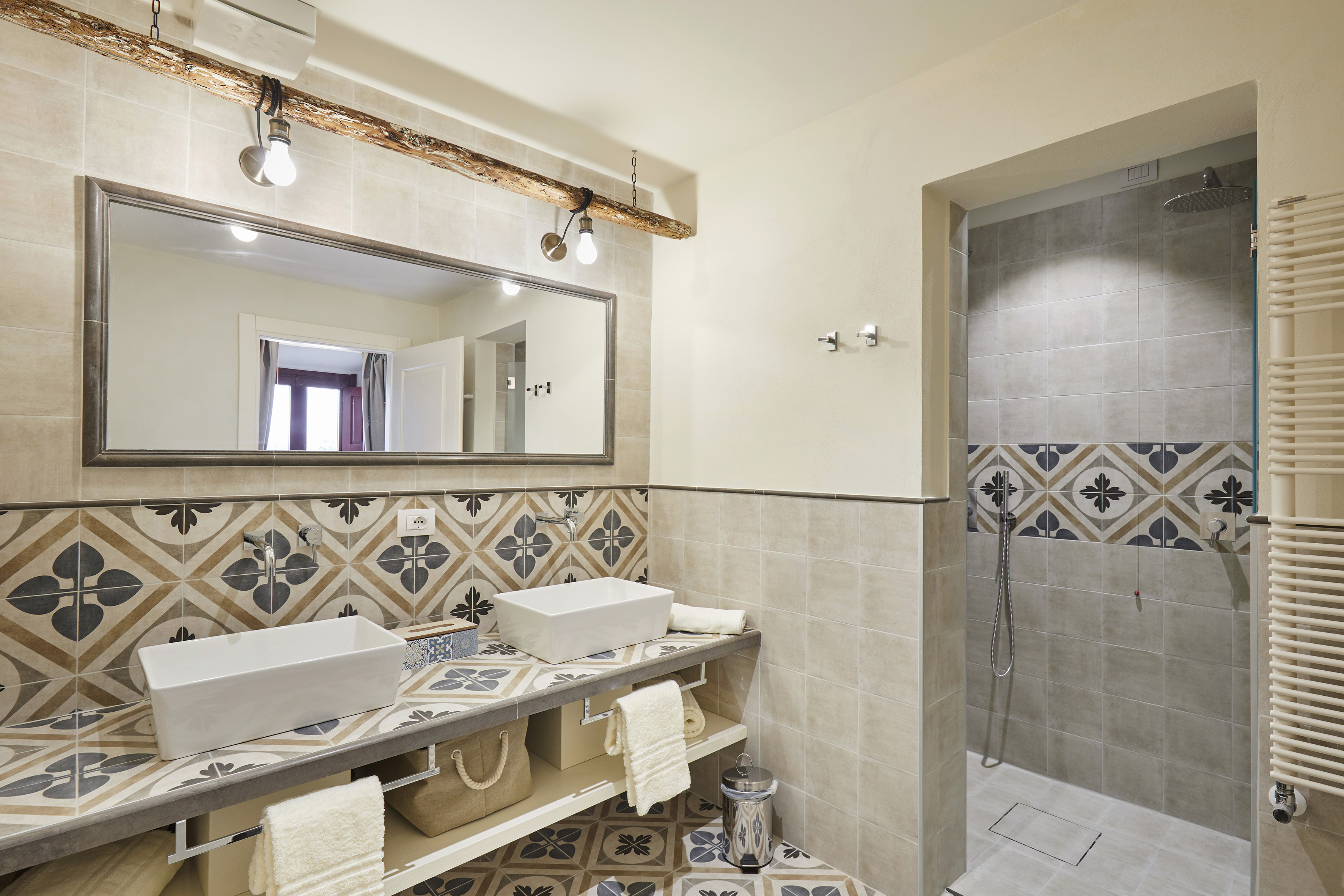 Mediterranean bathroom with double sinks, decorative tiles, and walk-in shower.
