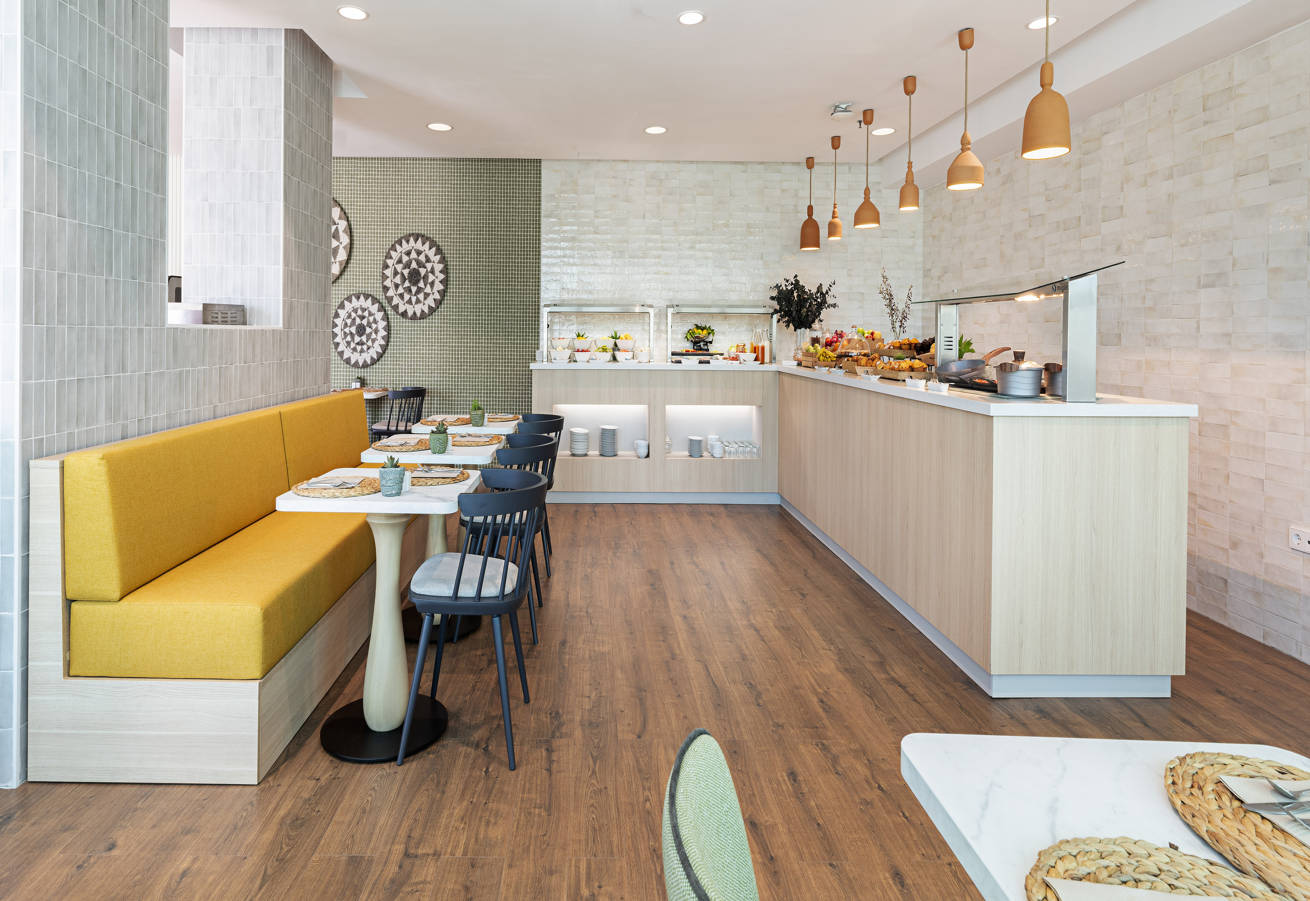 Modern buffet restaurant with yellow booth seating and food display.