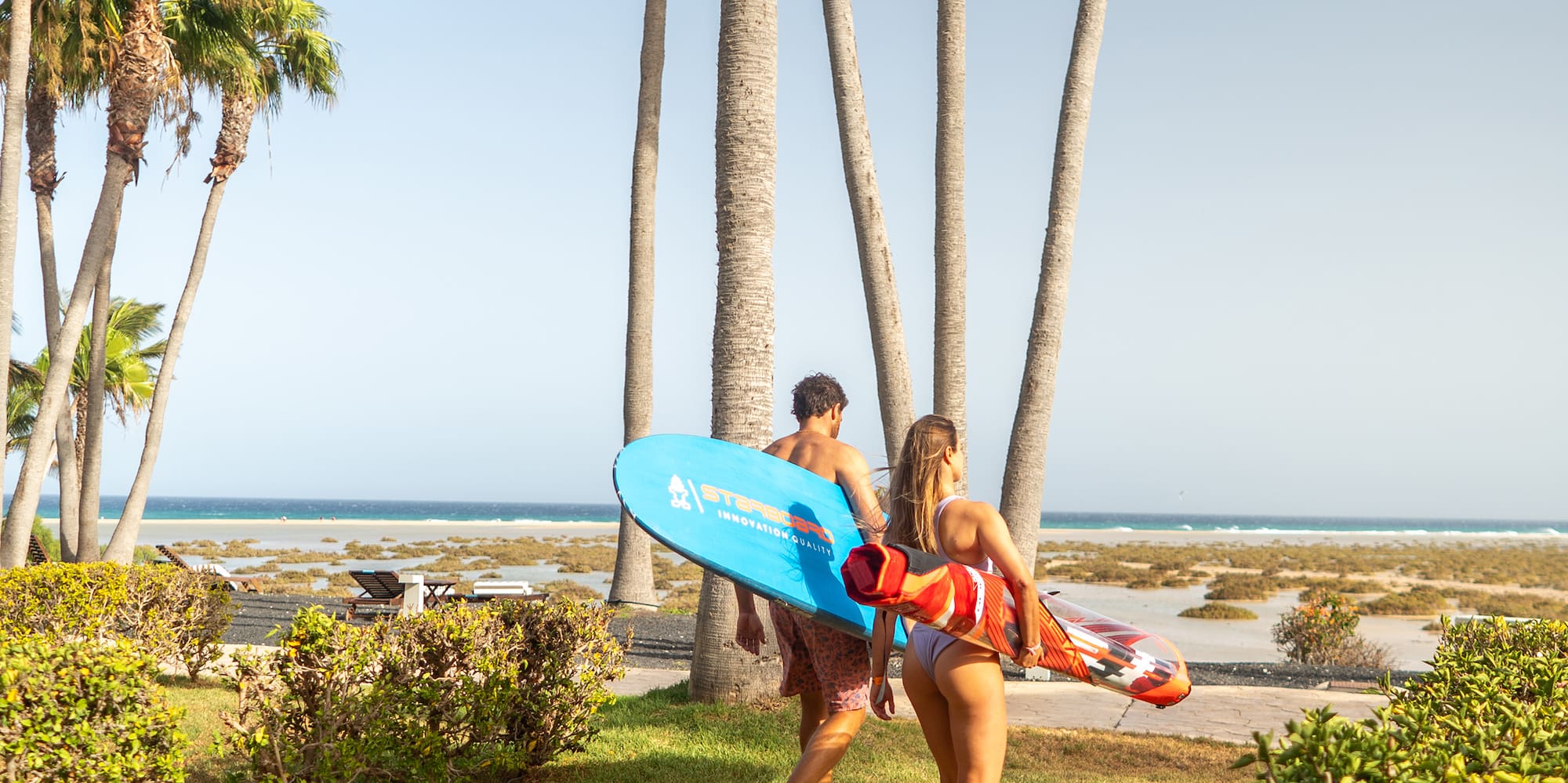 a man and woman carrying a surfboard