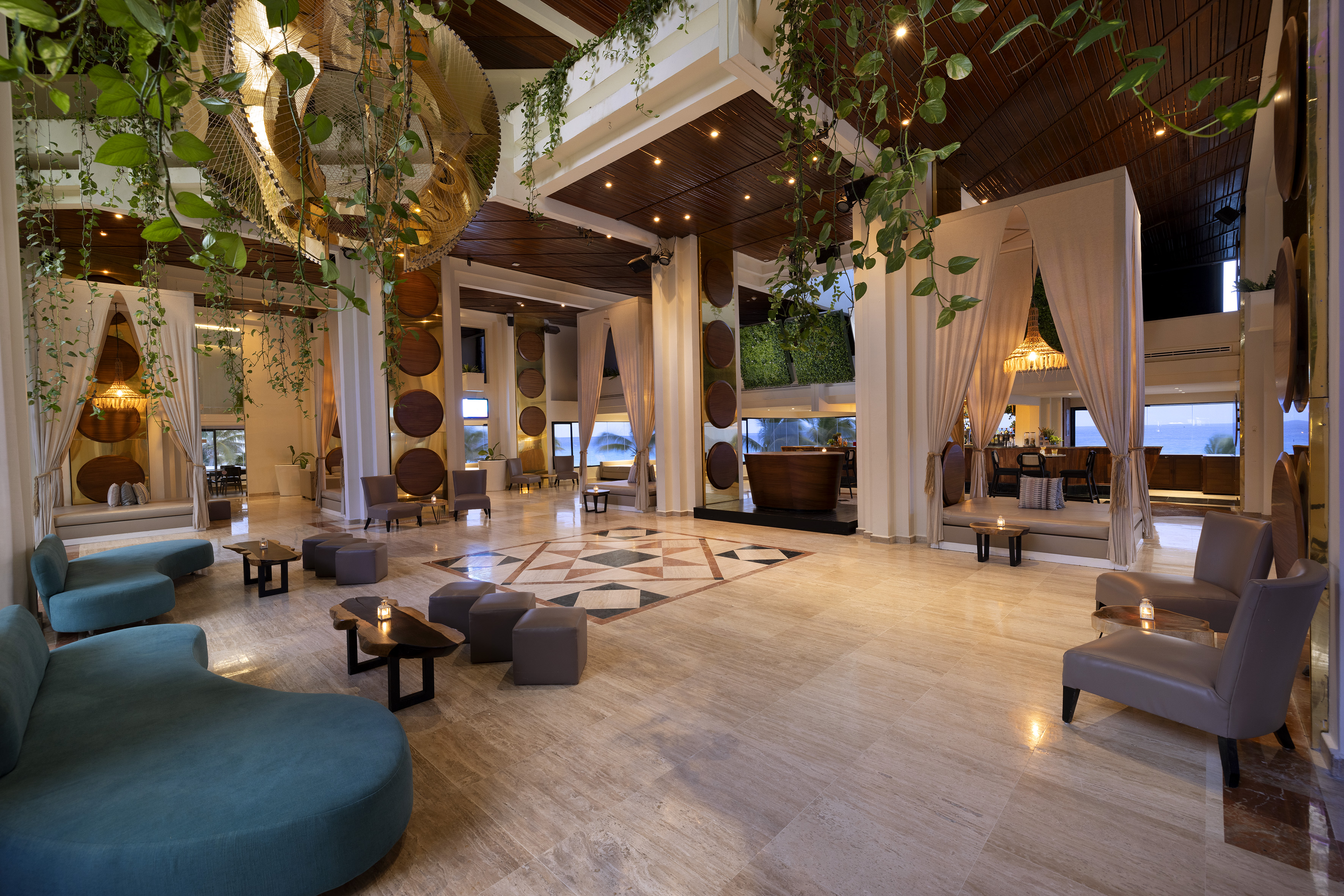 Modern tropical resort lobby with lush greenery, stylish seating, and ocean view.