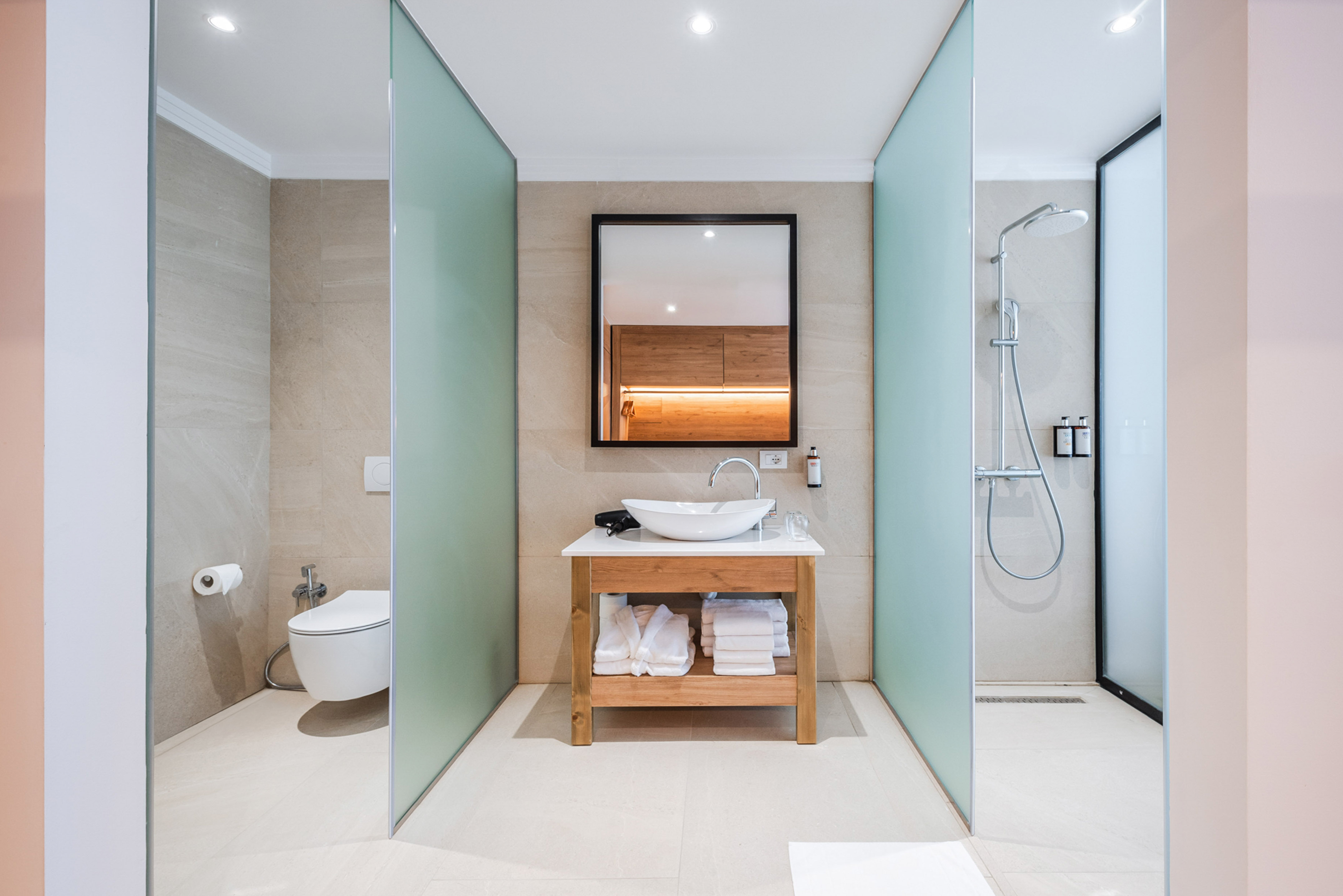 Modern bathroom featuring vanity, mirror, toilet, and glass shower enclosure.