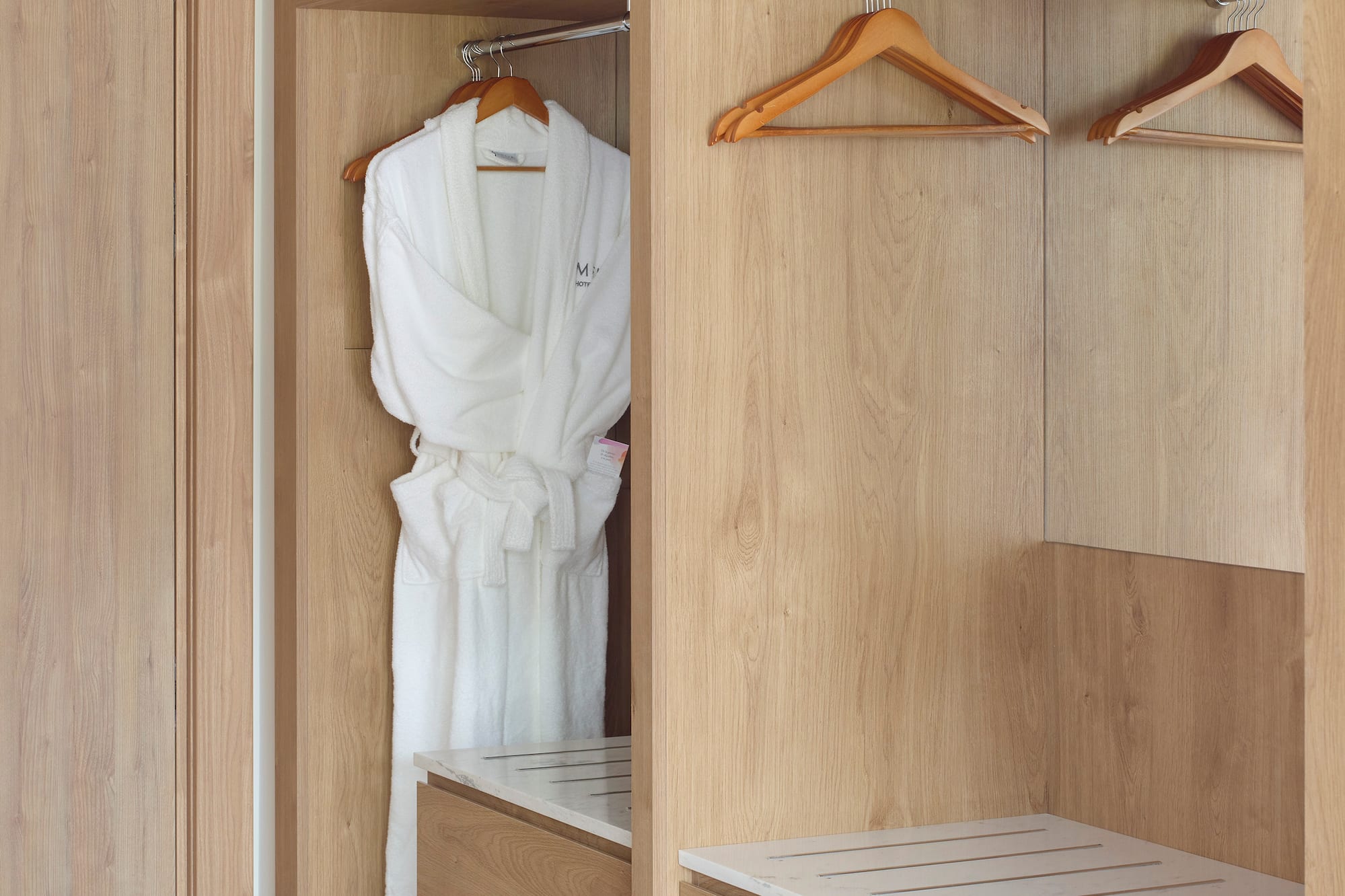 a closet with white robe and swingers