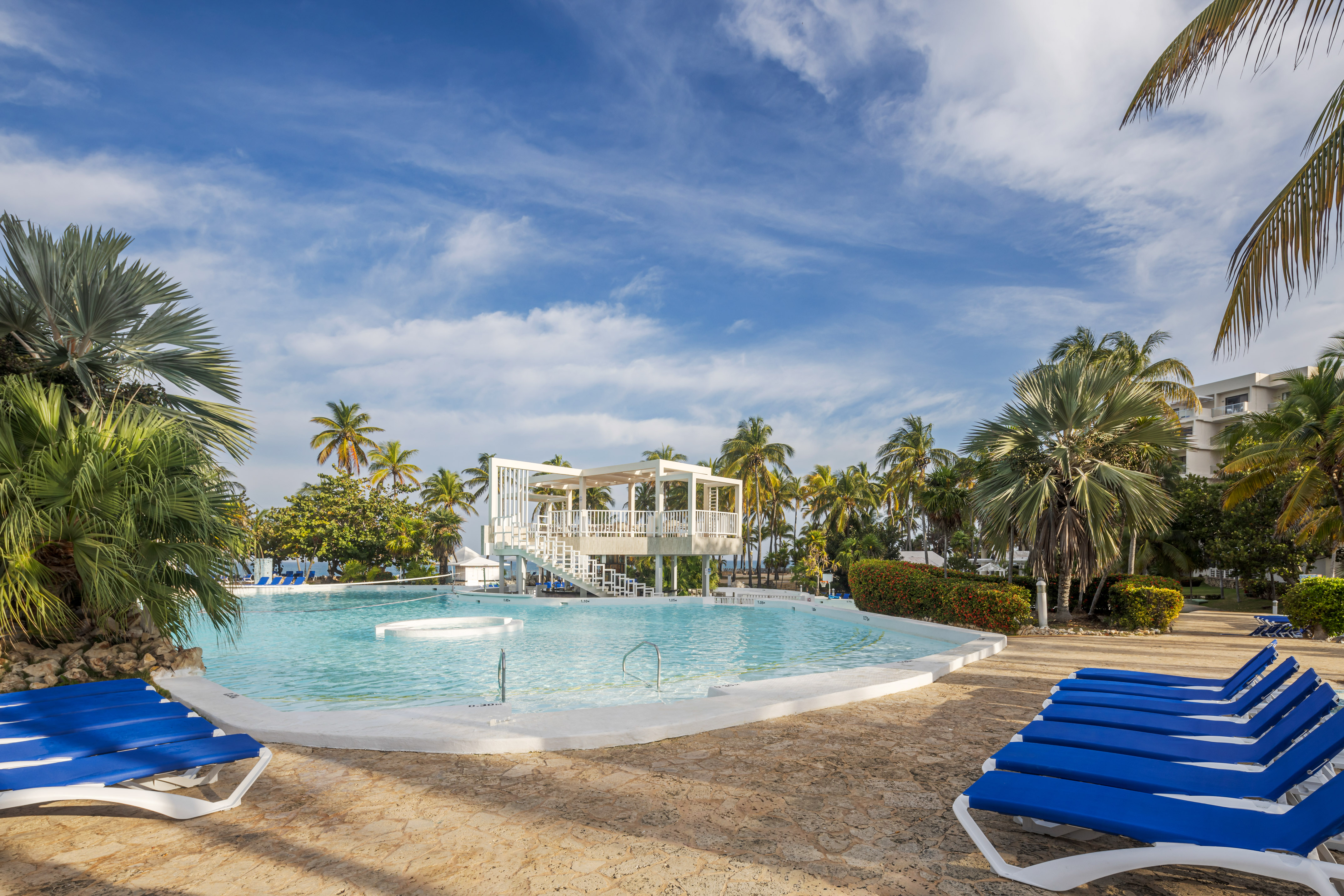 a pool with blue chairs and a gazebo in the middle