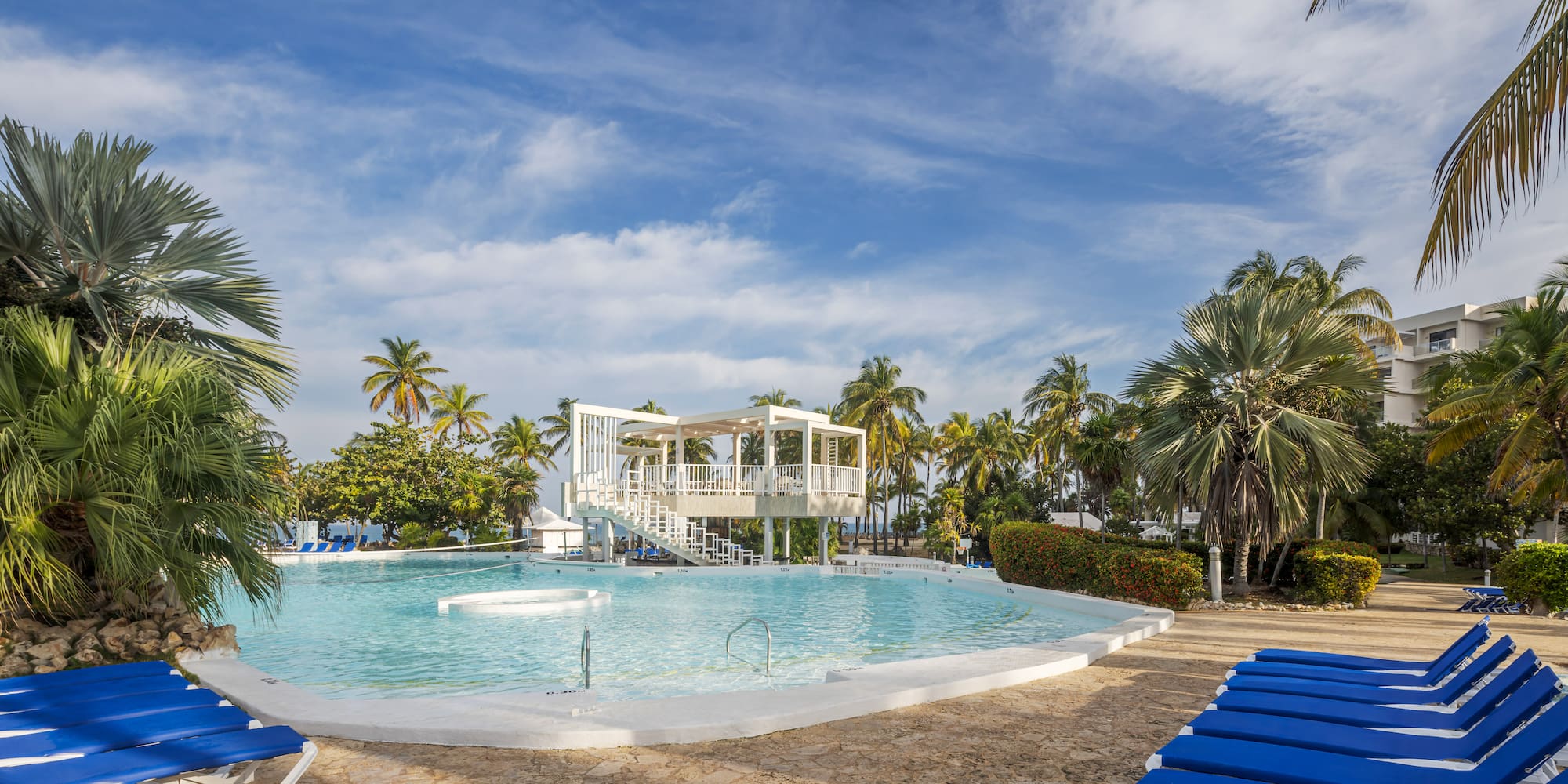 a pool with blue chairs and a gazebo in the middle