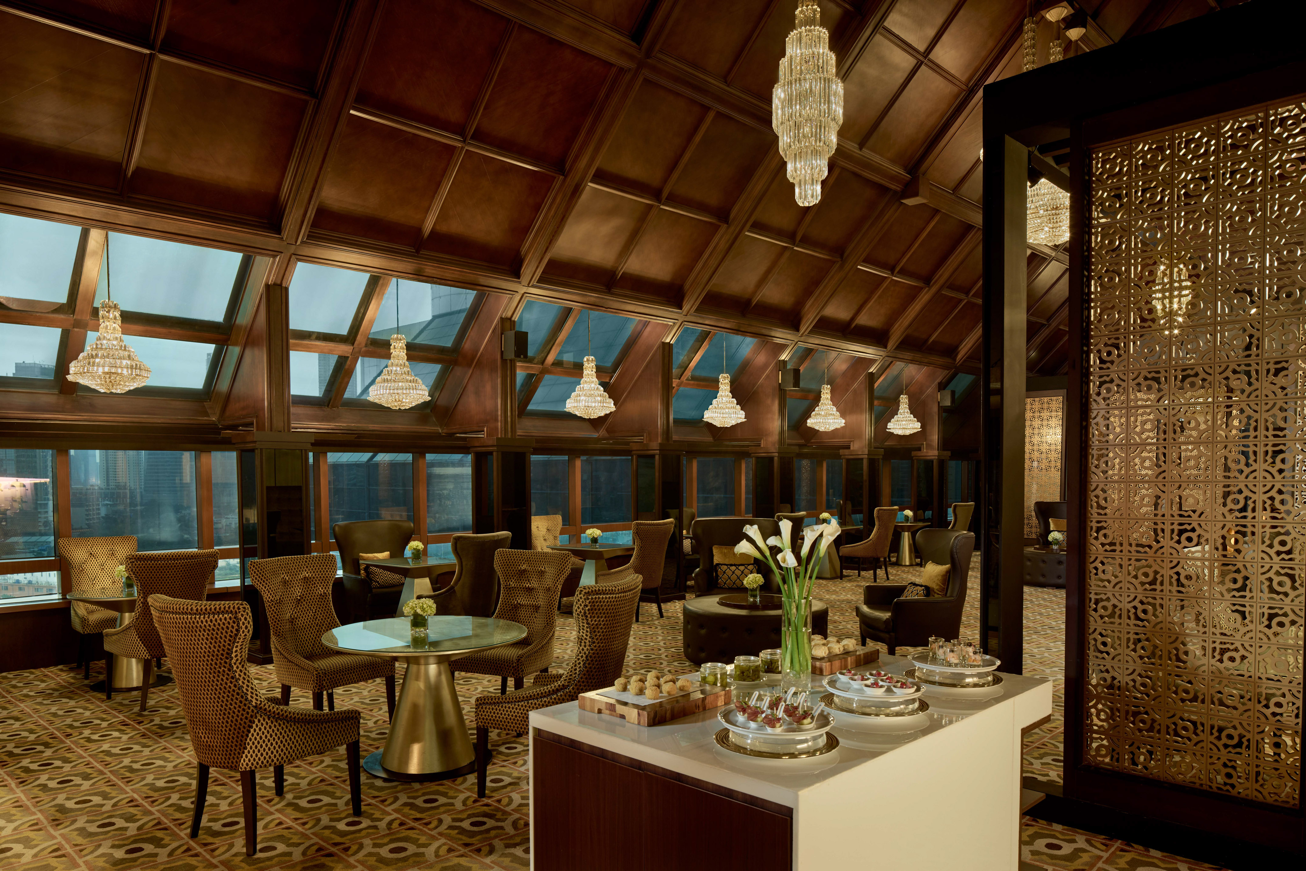 Luxury hotel lounge with crystal chandeliers, city views, and dessert bar.