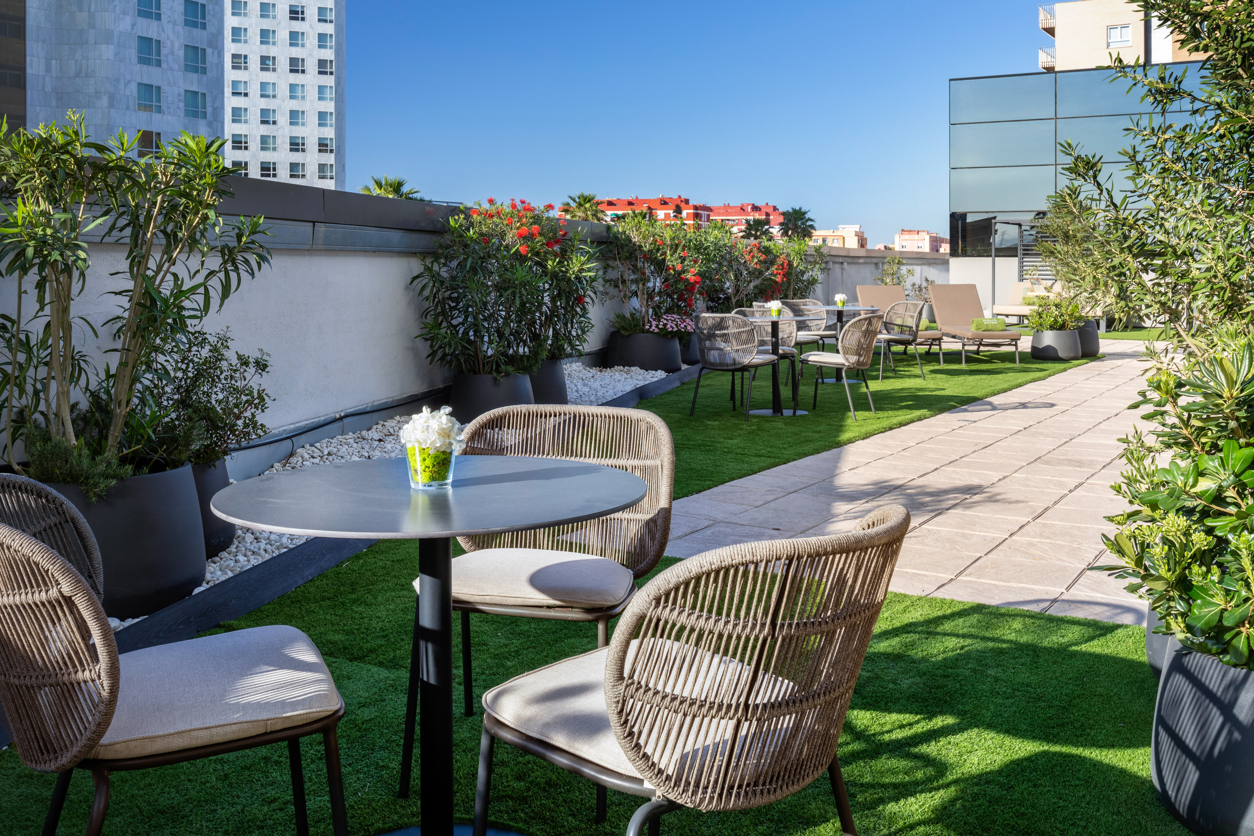 Rooftop terrace with outdoor patio seating, artificial grass, and flowering plants.