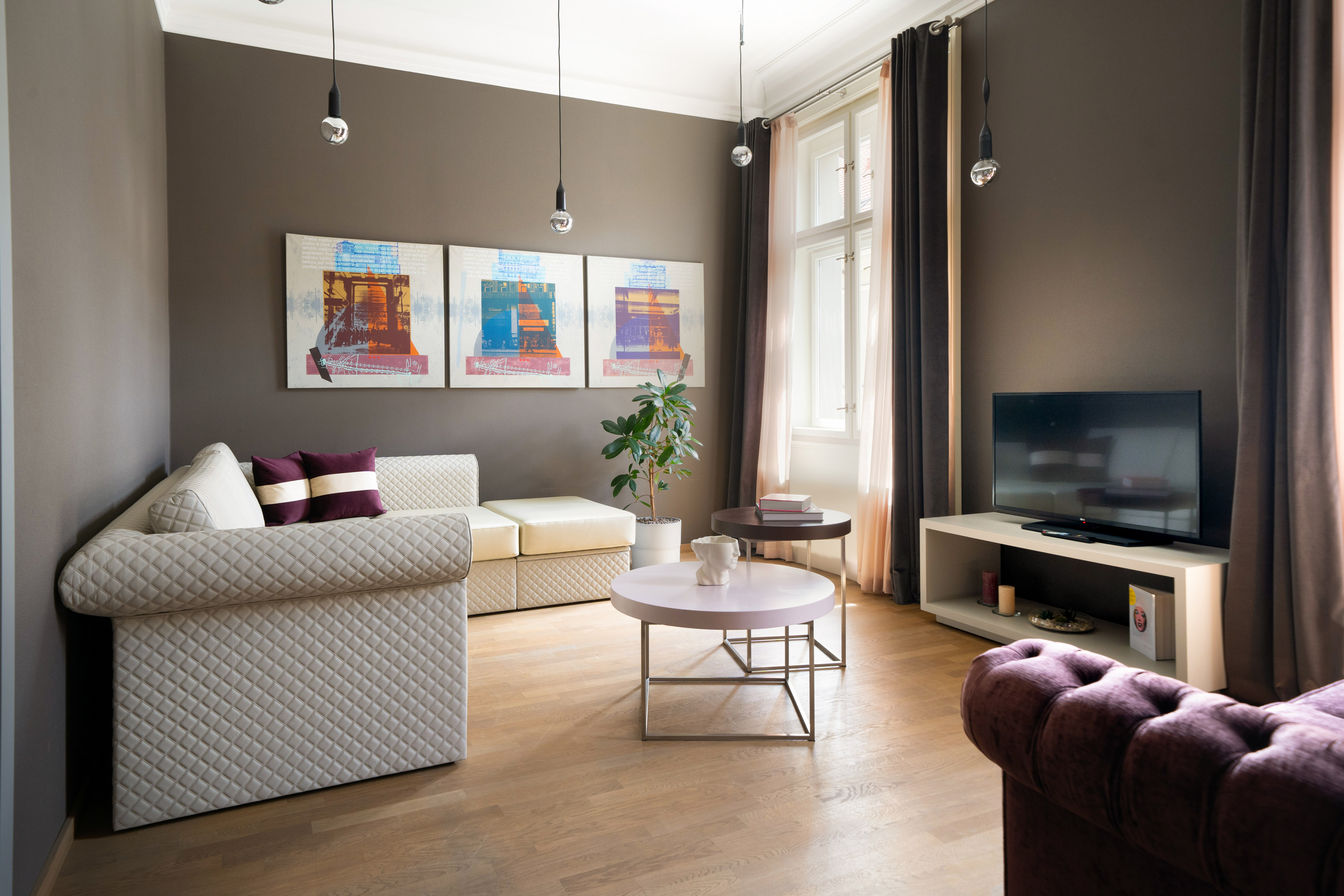 Cozy modern living room with sofa, wood floor, abstract art, and TV.