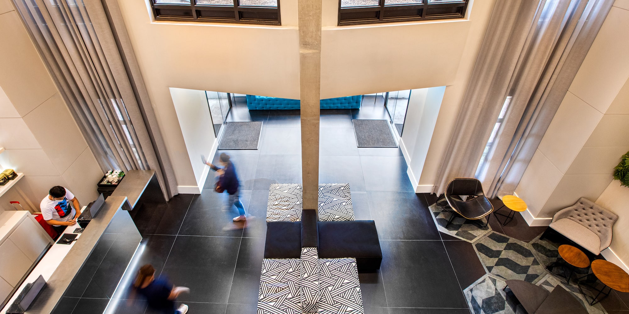 a room with a tall pillar and a couple of people walking