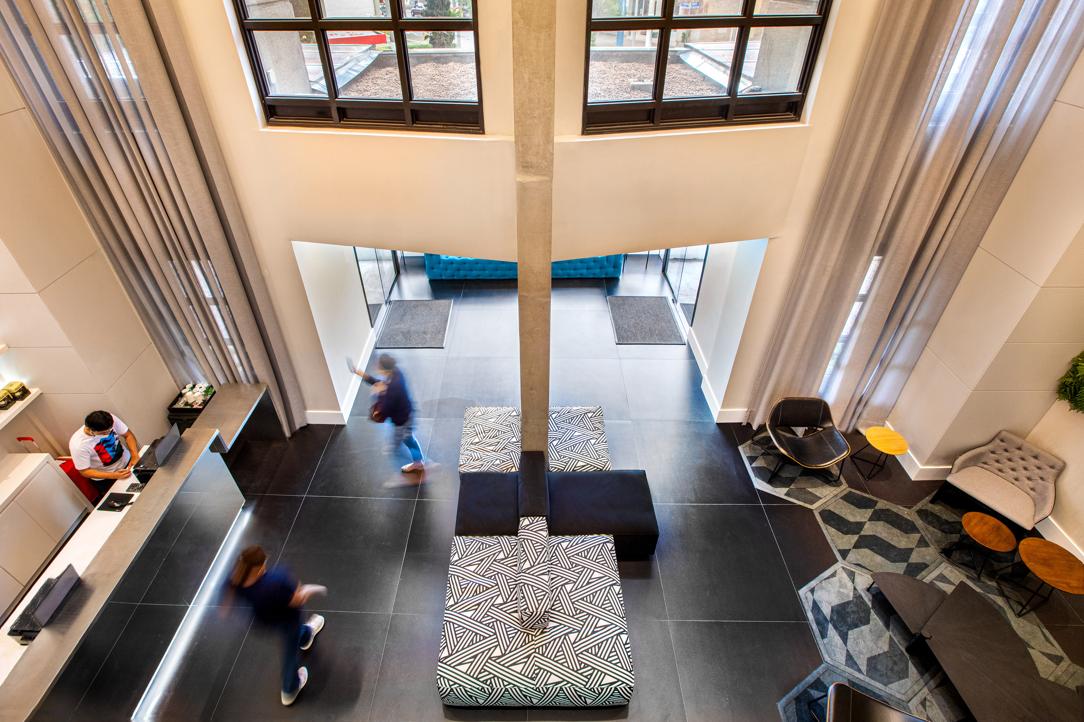 a room with a tall pillar and a couple of people walking